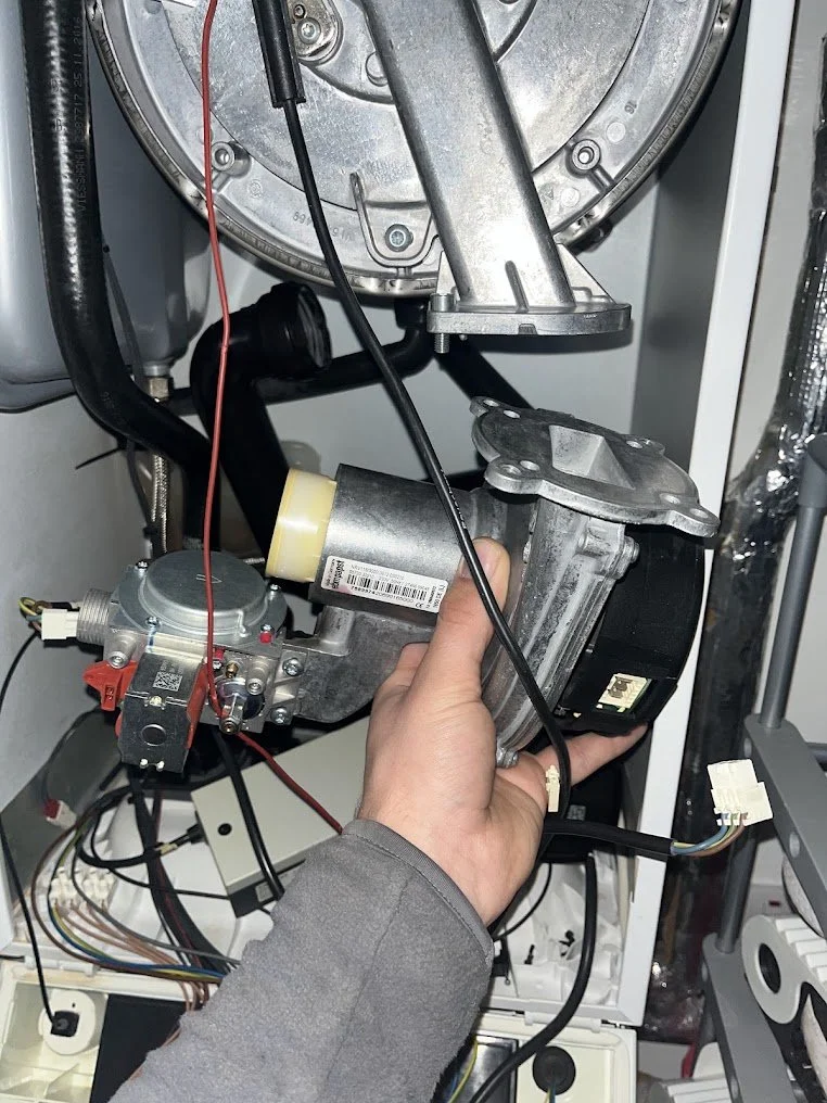 Person holding a motor component inside a washing machine, showing internal parts and wiring.