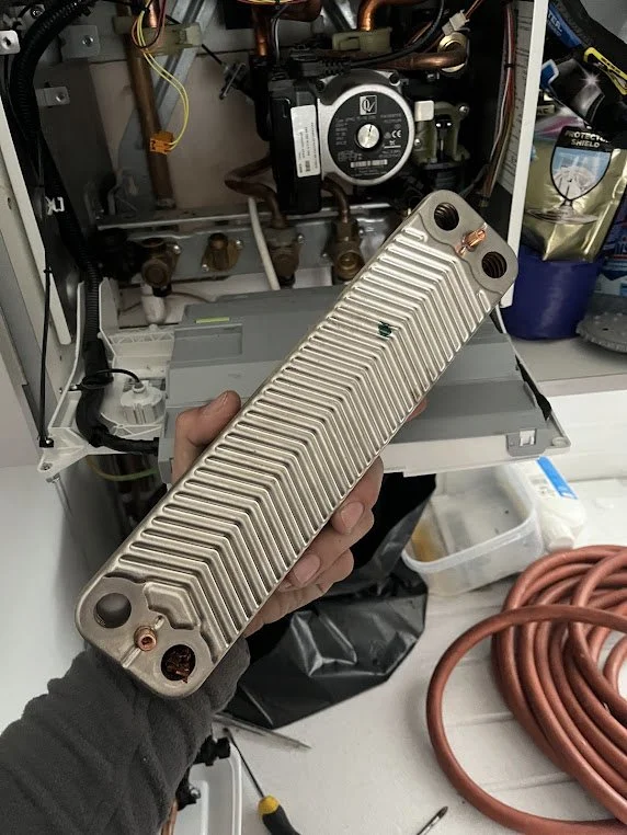 Person holding a heat exchanger or radiator in front of HVAC system and tools.