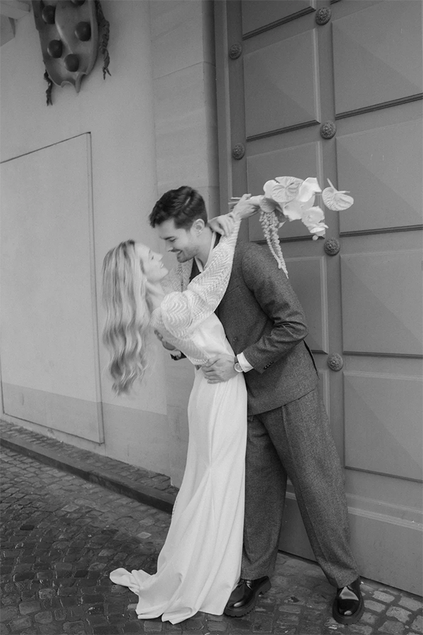 Wedding couple is hugging on the street. The bride is wearing a short dress from Marylise bridal.