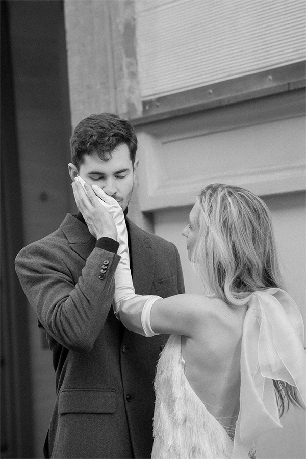 Groom is kissing the hand of the bride softly. She is wearing a short wedding dress from Marylise Bridal.