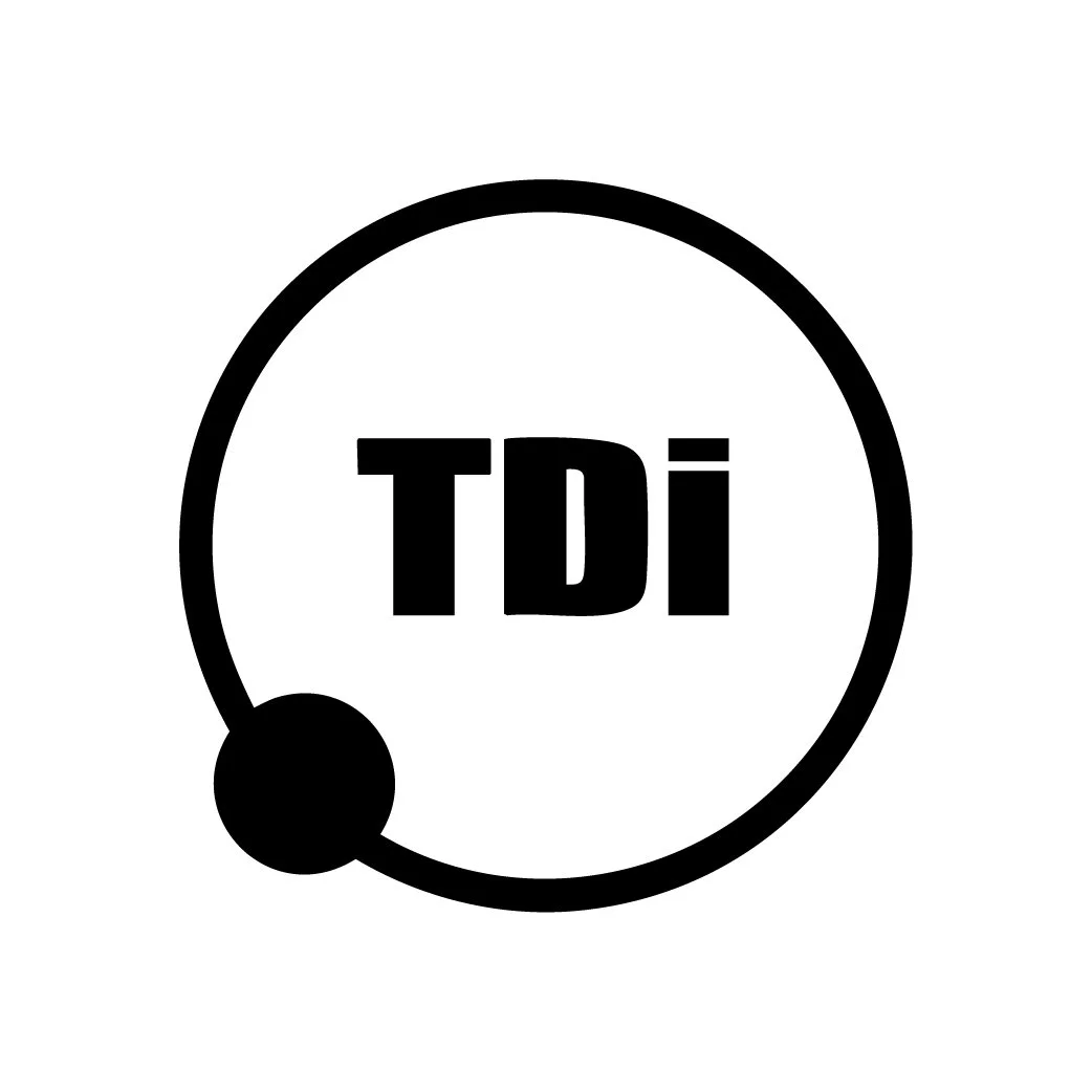 TDI logo in black and white with a circular design and a small black circle at the bottom left
