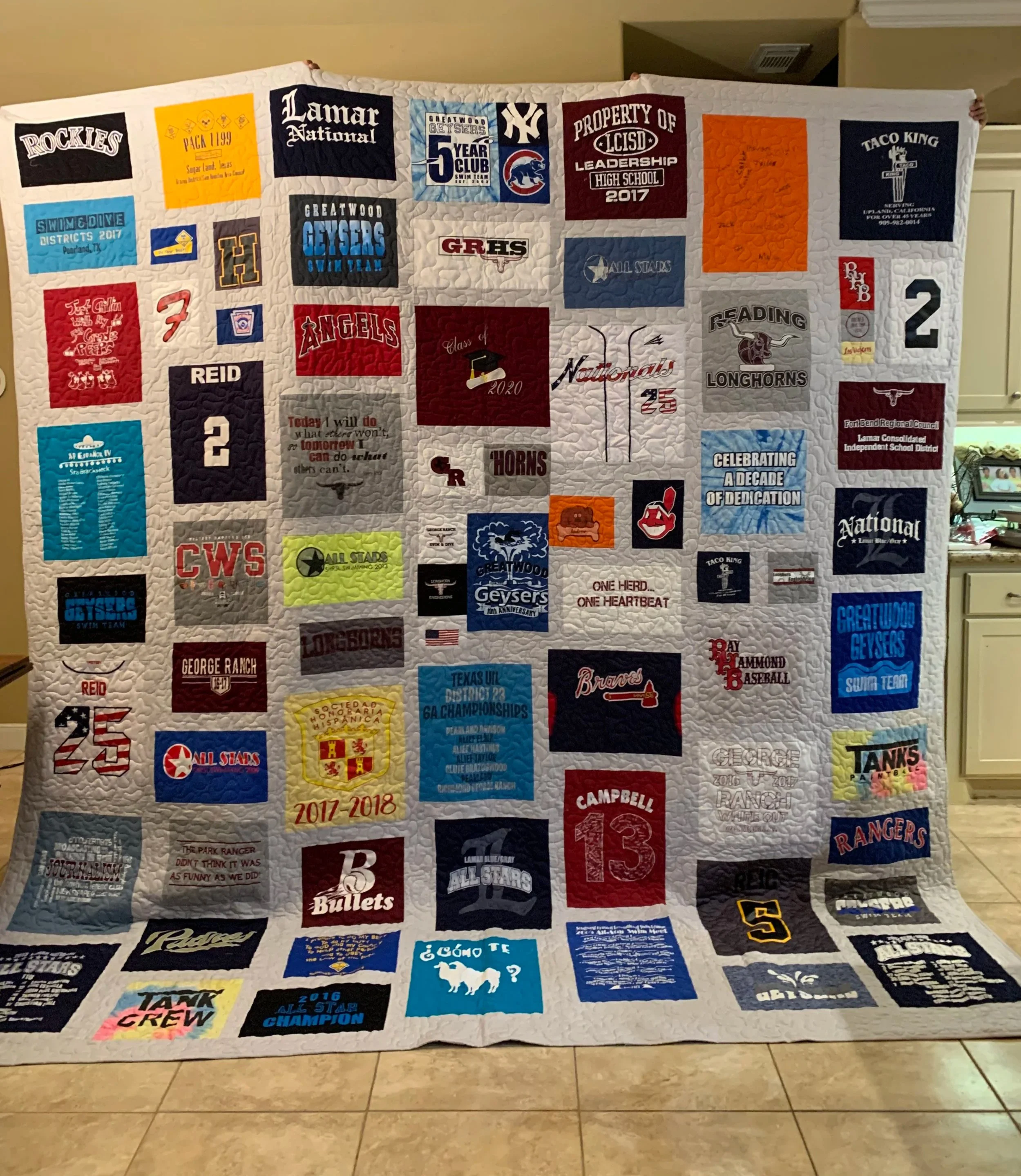 A T-shirt quilt with various school and sports team logos, names, and achievements embroidered on it. Fantastic graduation gift.