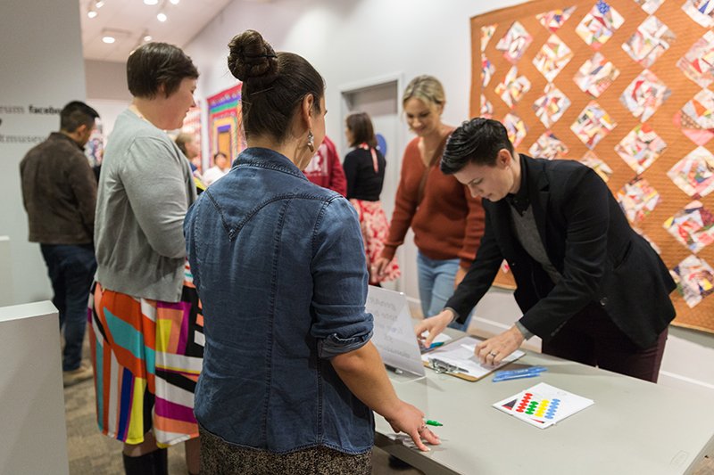 People browsing and purchasing at an arts and crafts exhibit or market.