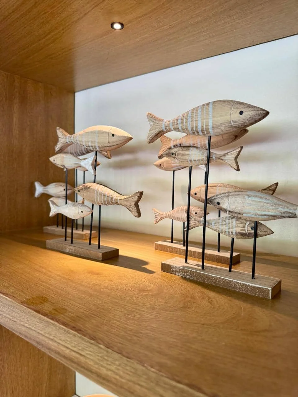 Decoración con figuras de peces de madera en una estantería de madera.