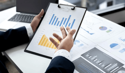 Persona revisando informes con gráficos en una tableta en una oficina.