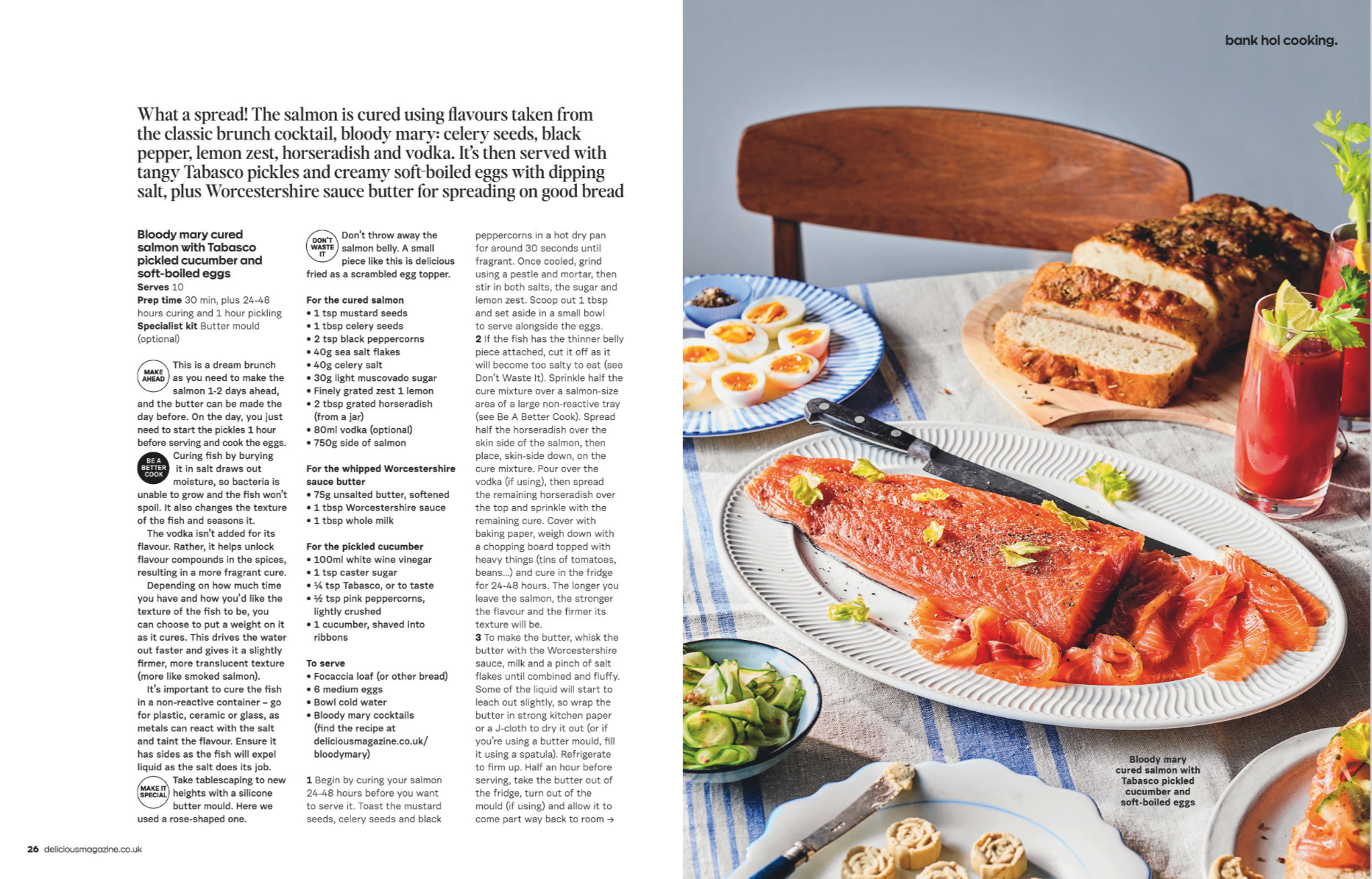 Open cookbook with salmon dish, boiled eggs, bread, and drinks on table.