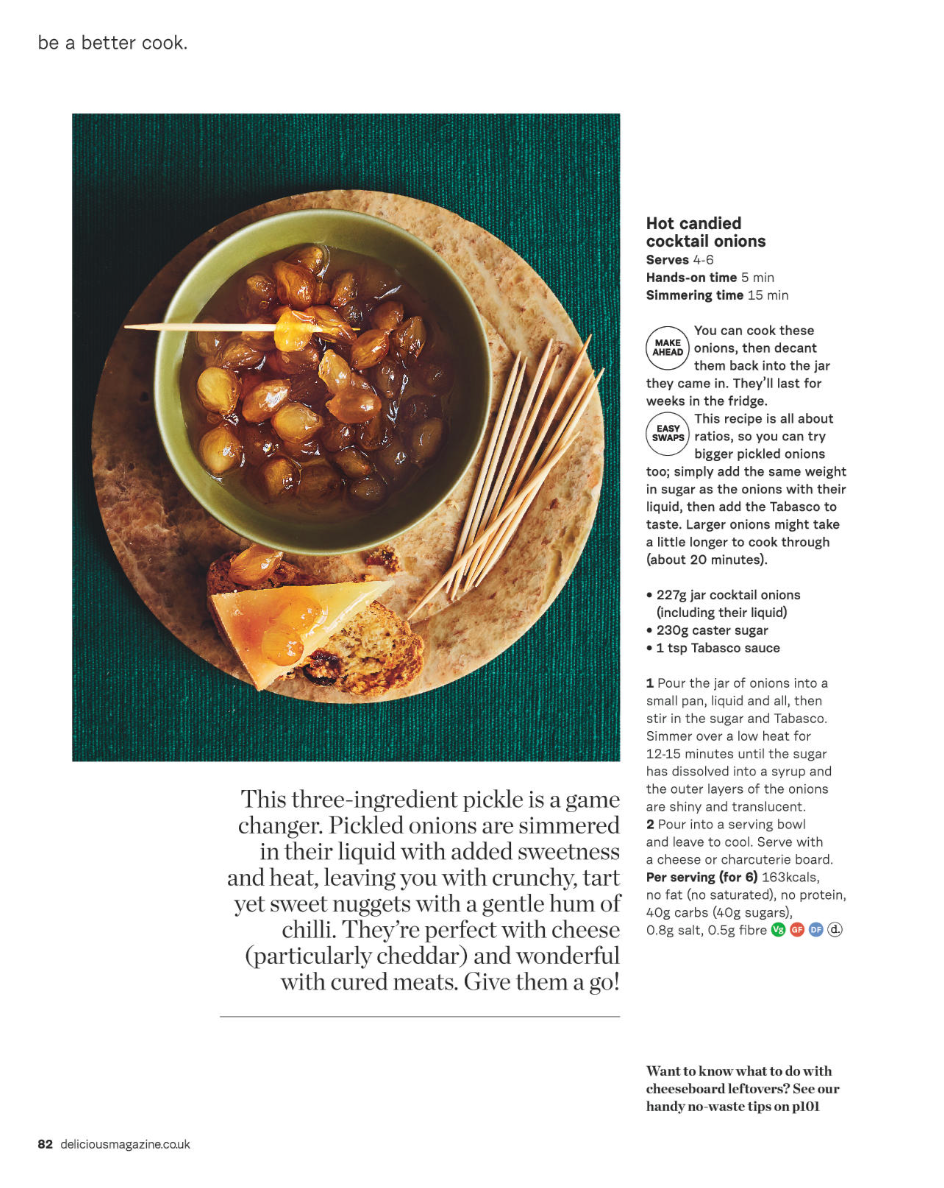 Plate with a bowl of candied cocktail onions, a piece of cheese on bread, and a breadstick, with a green cloth background.