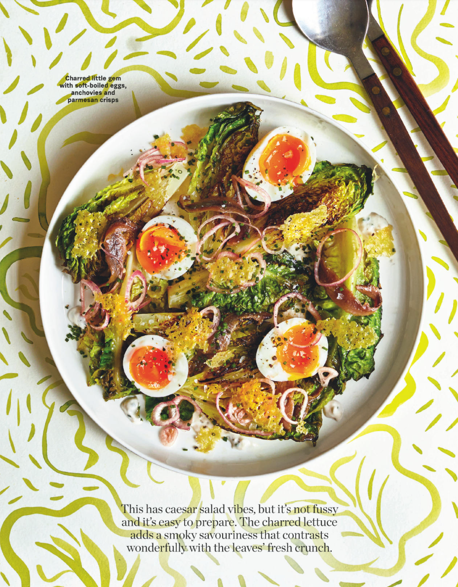 Charred lettuce salad with soft-boiled eggs, red onions, crispy parmesan, and greens, served on a white plate.