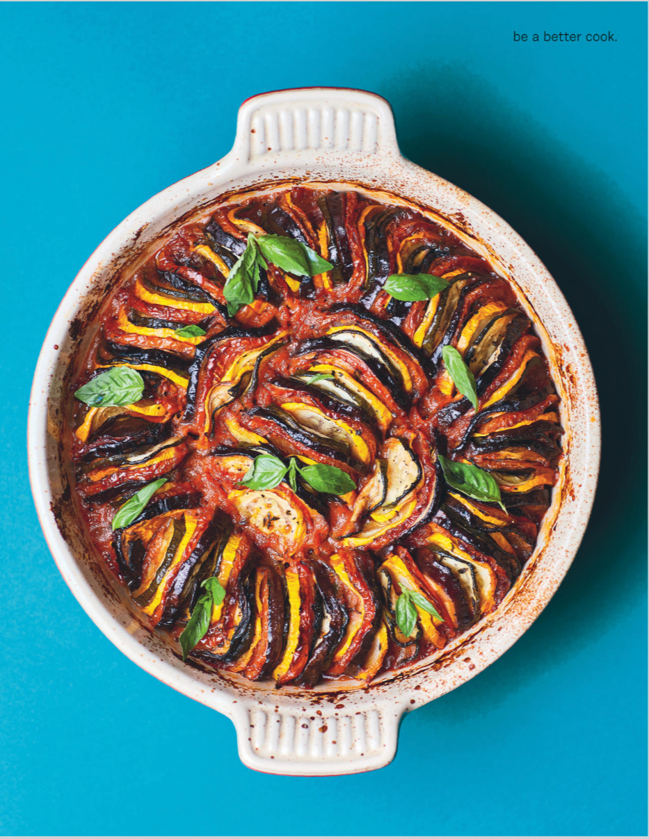 Baked eggplant Parmesan with tomato sauce and basil in a white oval dish.