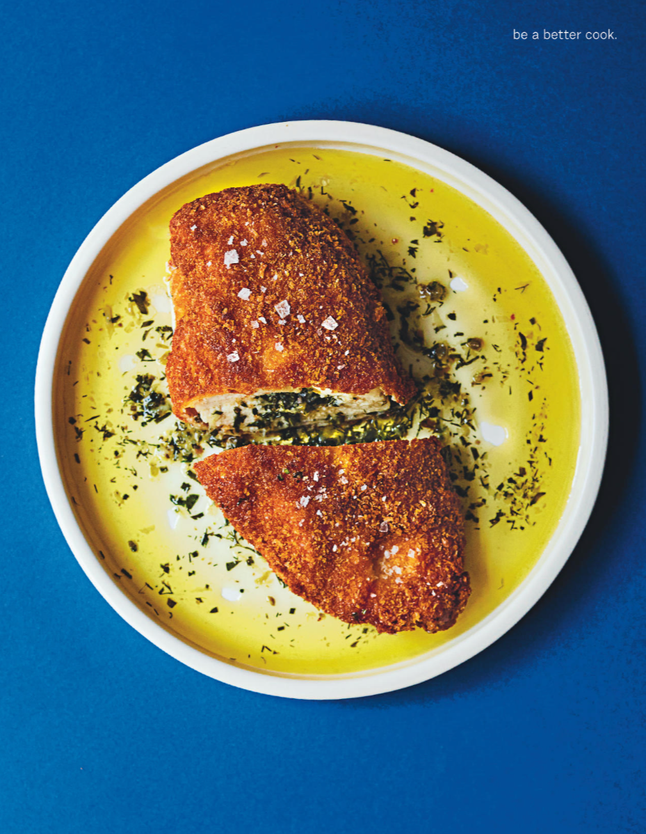 Fried fish fillet in olive oil with herbs, served in a white bowl on a blue background. Text in the top right corner reads 'be a better cook.'