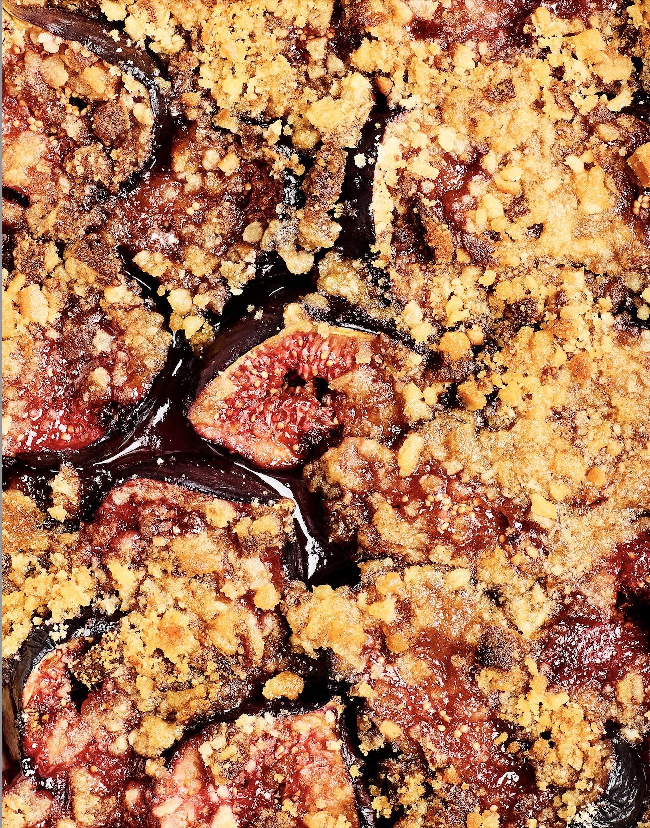 Close-up of a baked fruit crumble featuring sliced figs with a golden crumb topping.