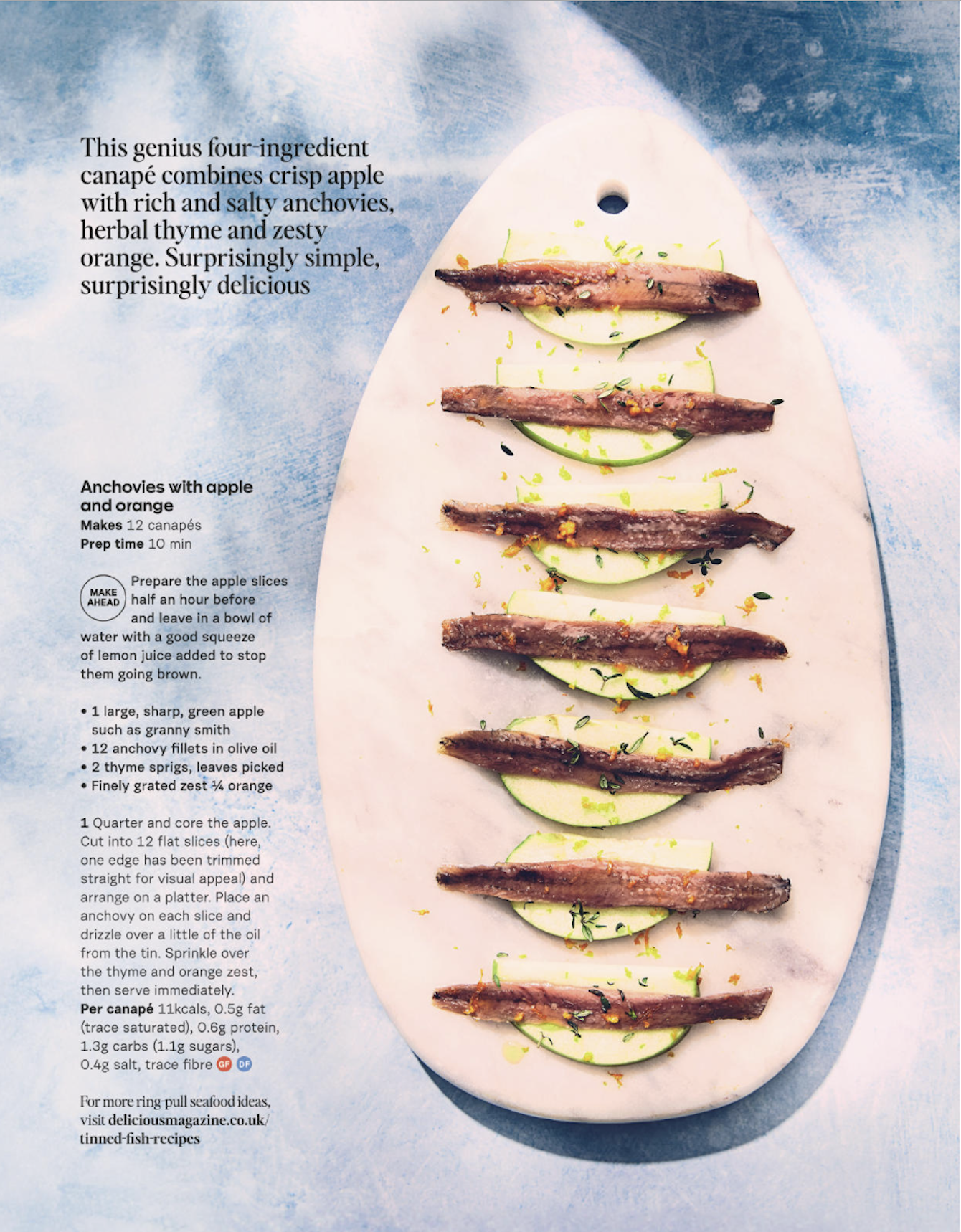 Plate with apple slices topped with anchovies, garnished with herbs and orange zest, with a side of lemon wedges.