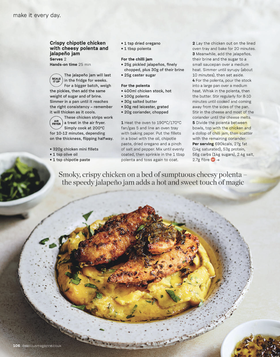 A plate of crispy chicken on cheesy polenta with jalapeño jam, garnished with chopped herbs.