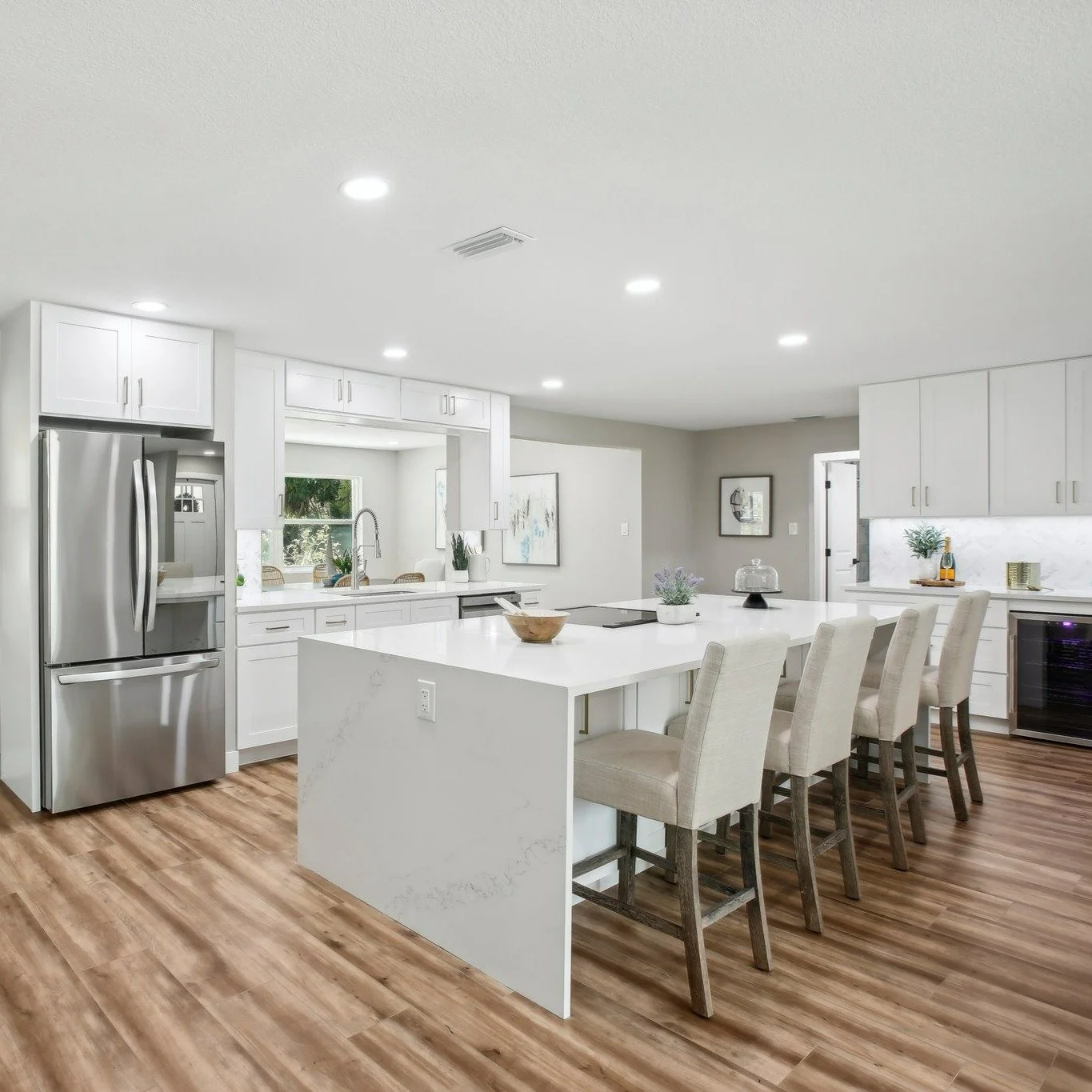 Before ➡️ After: This St. Pete kitchen went from boxy and dim to bright and functional. We opened the layout for better flow, added a waterfall island with seating, installed durable wood-look LVP, and finished it with classic white cabinetry + moder