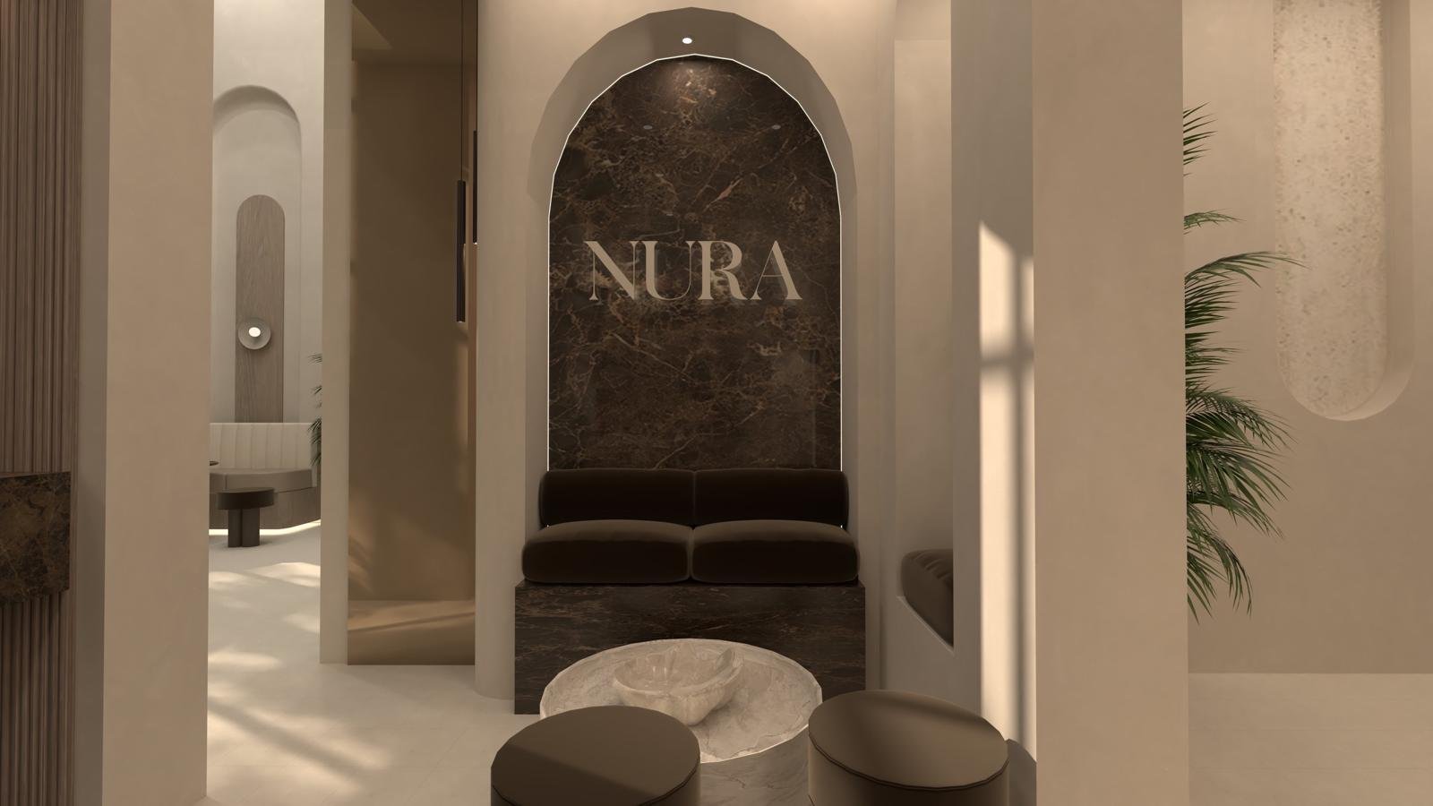 Lobby with brown marble back wall displaying the word NURA, a brown velvet bench, a round marble coffee table, and two round ottomans.