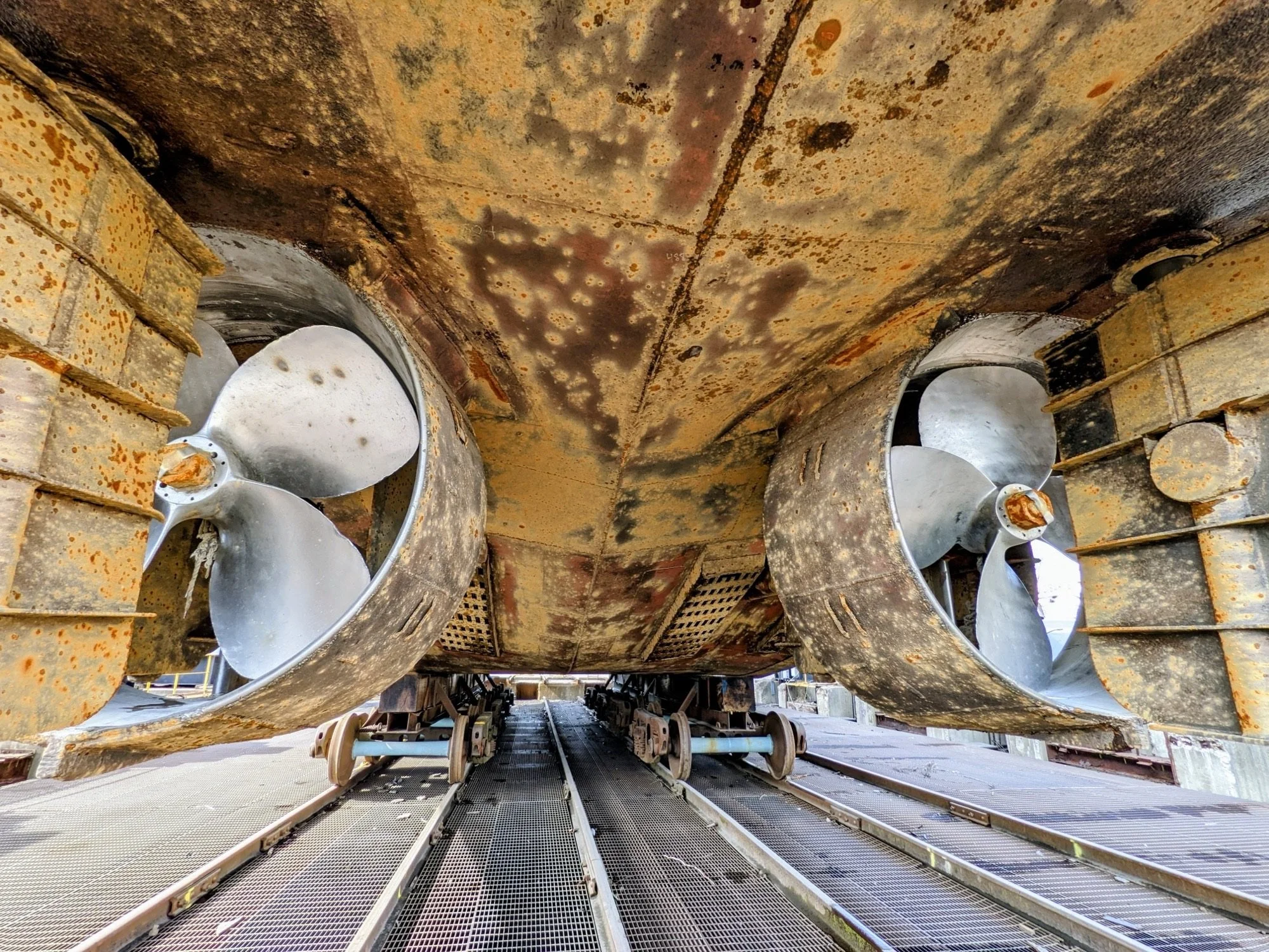 Underwater view of submarine propellers with rusted and worn metal hull.