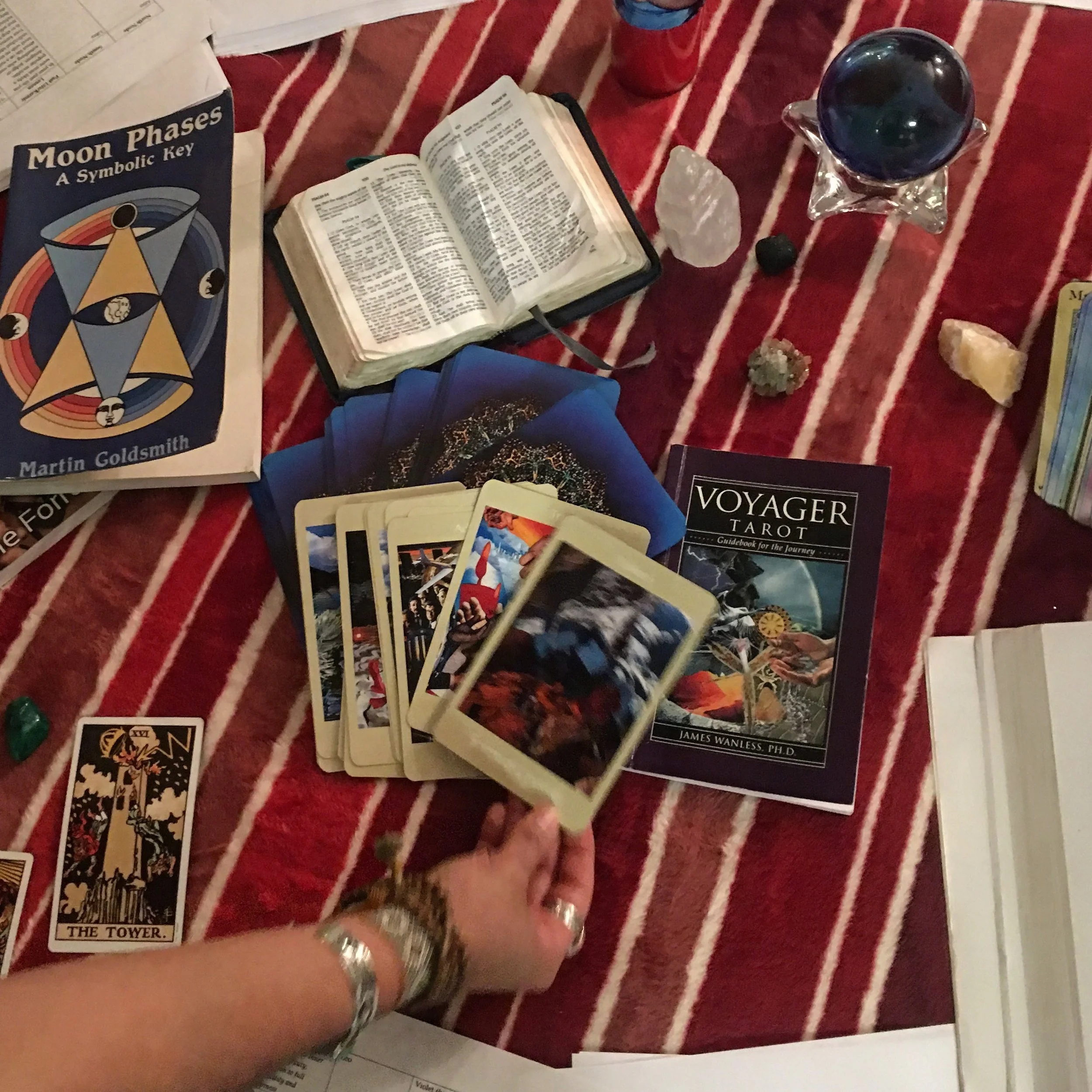 table with various divination tools like crystal ball, tarot, and moon phases book