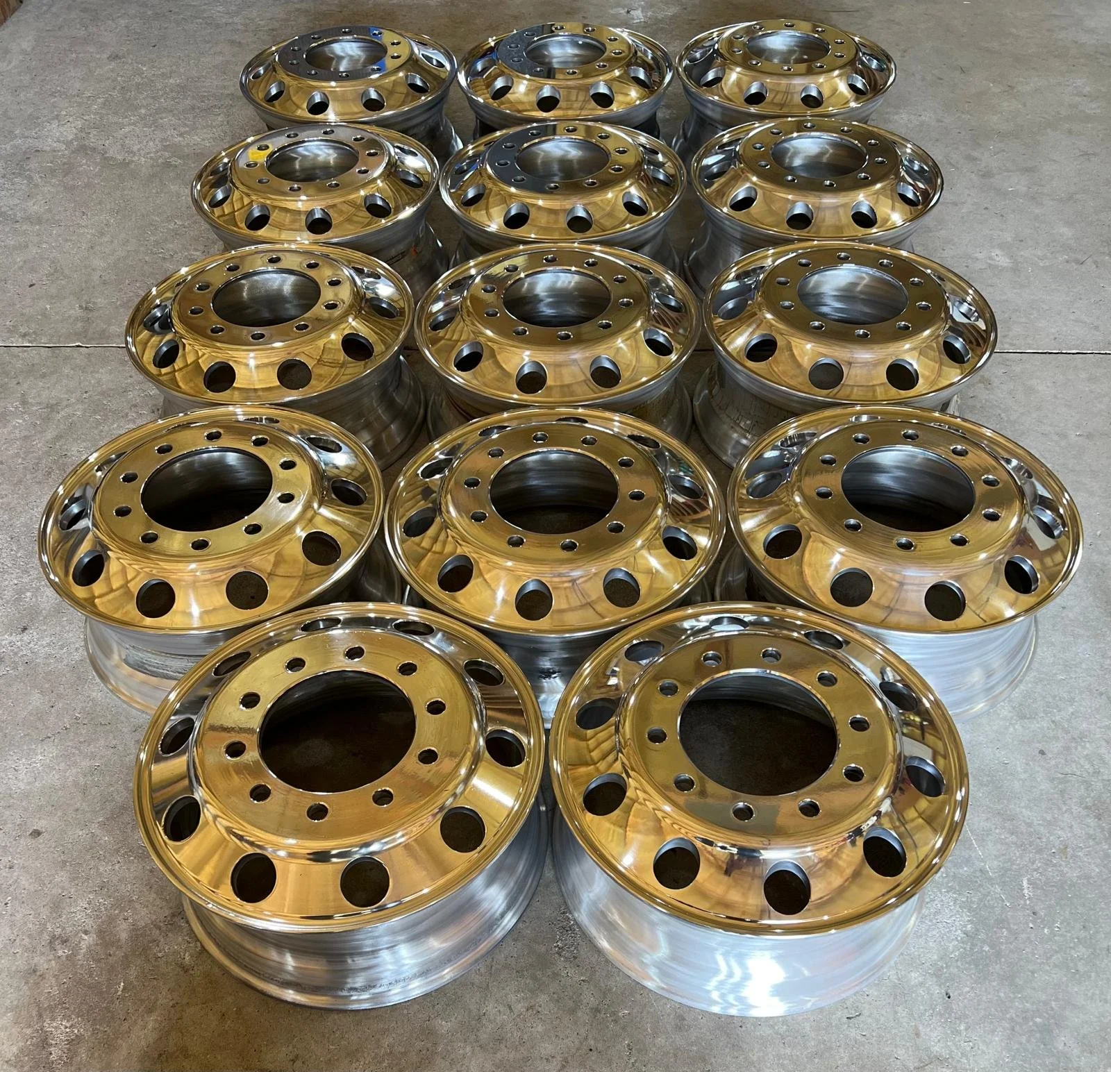 A group of shiny, gold-colored steel wheel rims arranged on a concrete floor.