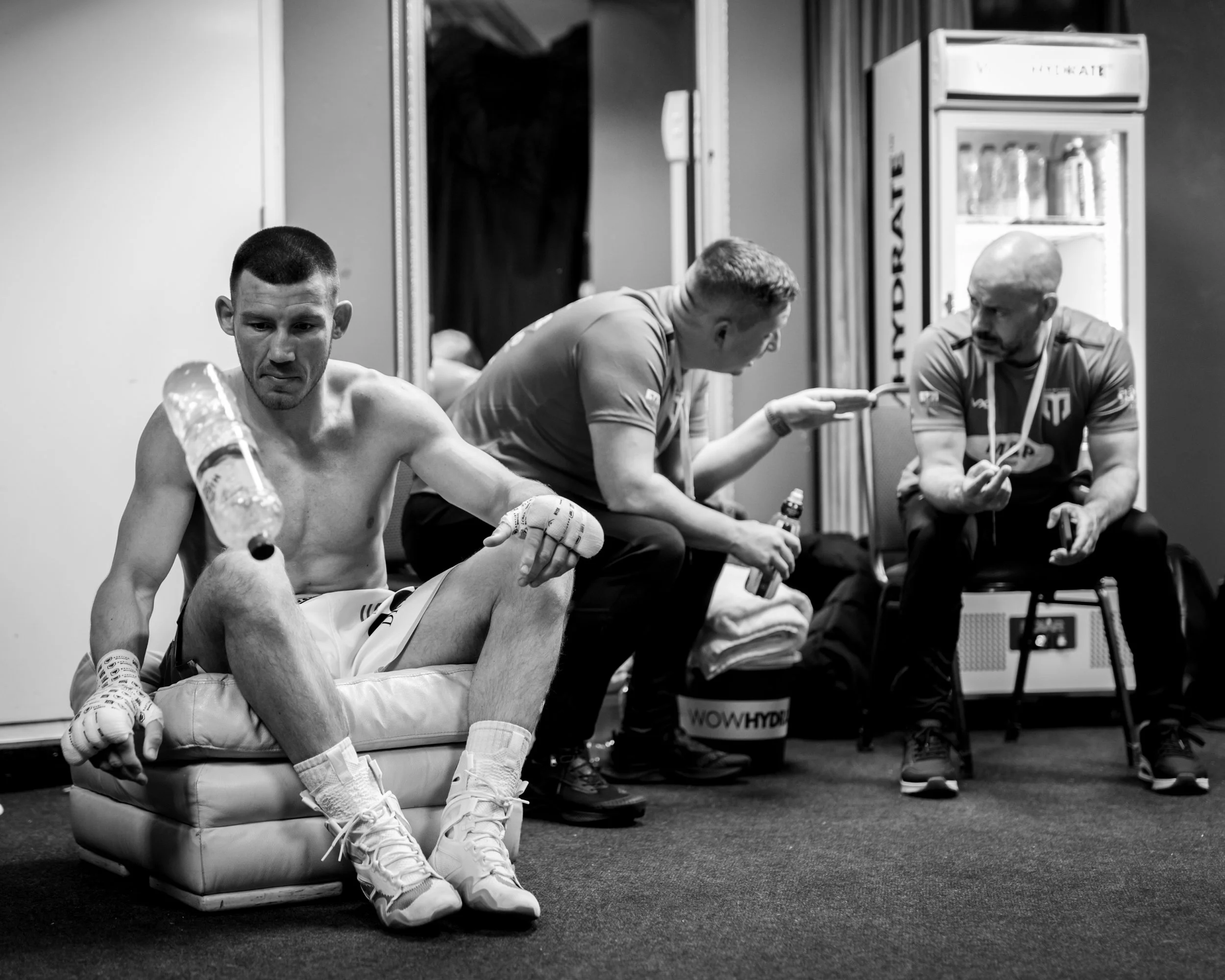 Liam Williams flips a bottle in boredom whilst Brett Parry and Adam Booth exchange notes, backstage in the CIA Cardiff 
