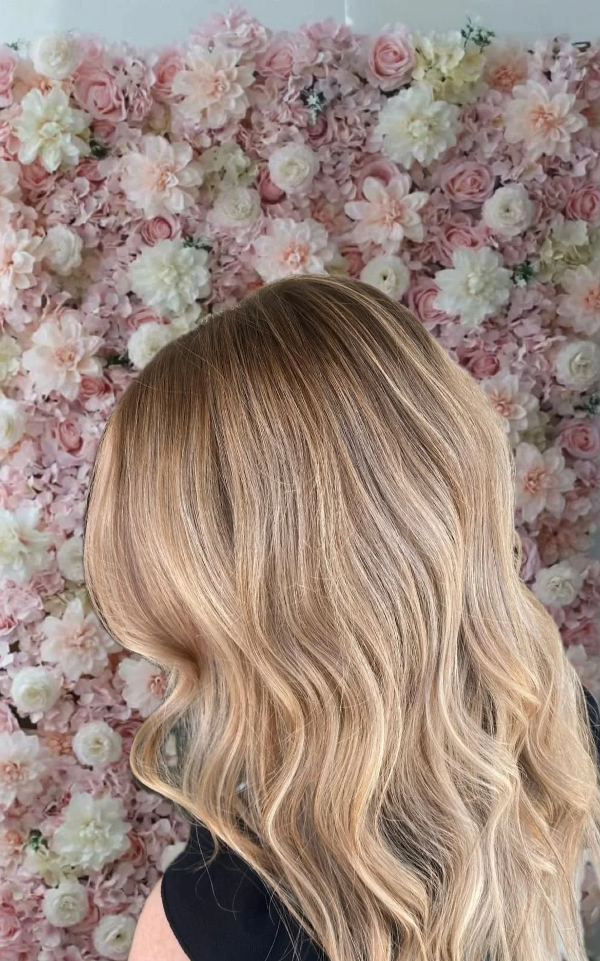 Close-up of wavy blonde hair against a background of pink and white flowers.