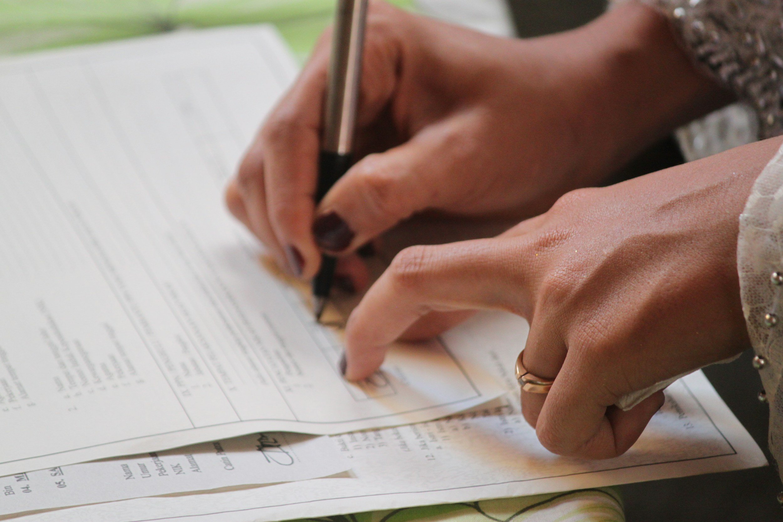 Close-up of hands signing a document with a pen on a table.
