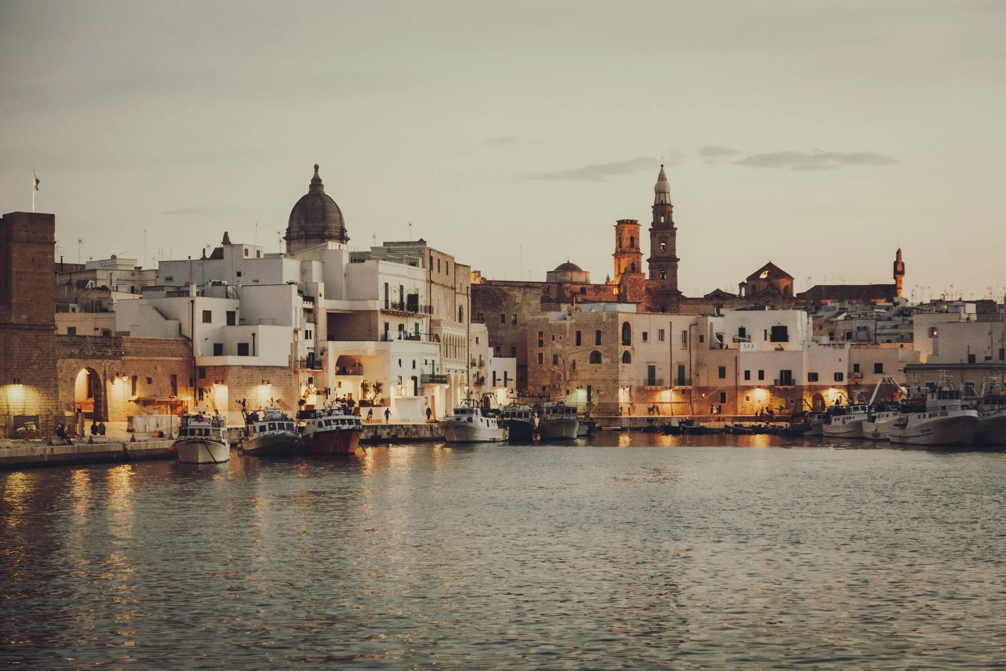 Fine art print photography for modern living room wall decor in Zürich.. Sunset over a harbor with boats docked and historic buildings with church steeples in the background.