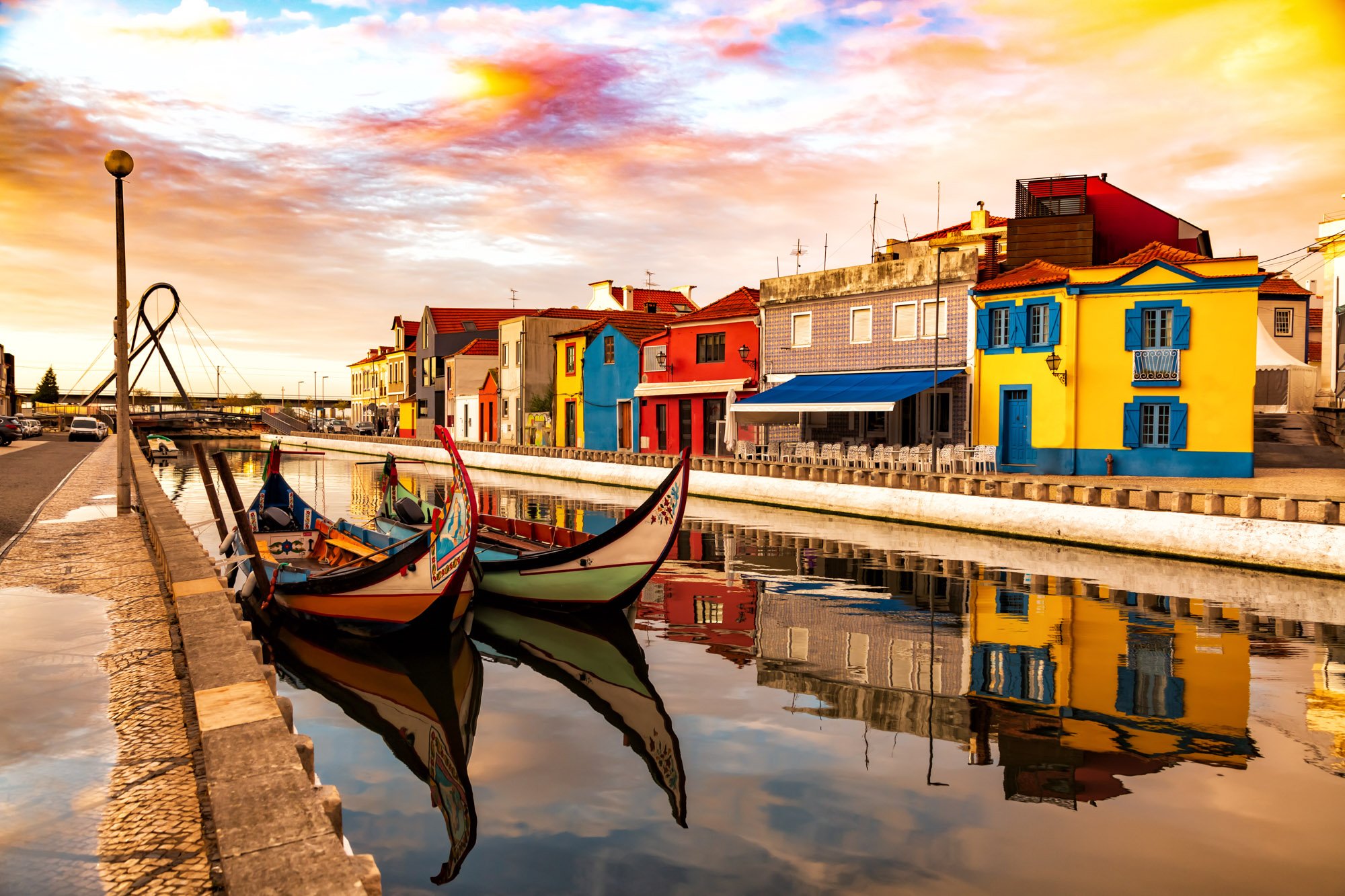 Colorful buildings along a canal with gondolas in the foreground, under a vibrant sunset sky.