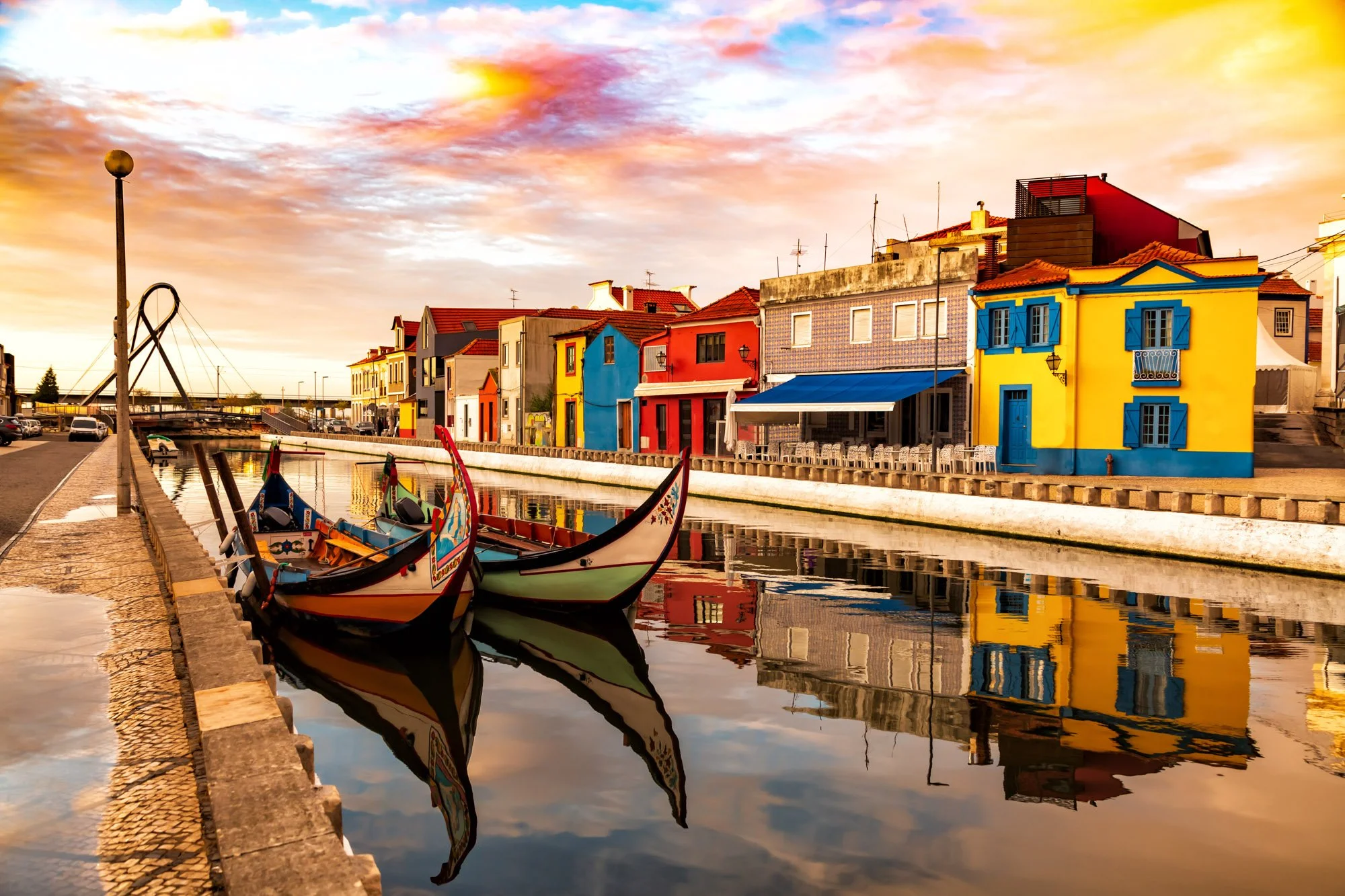 Colorful buildings and boats along a canal at sunset with a cloudy sky reflecting in the water.