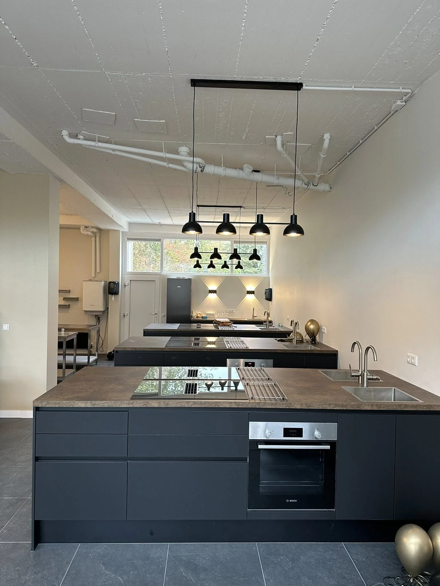 Installatie van een kookgroep voor inductie kookplaten en design hangverlichting in een moderne kookstudio door elektricien Stoker Elektro.