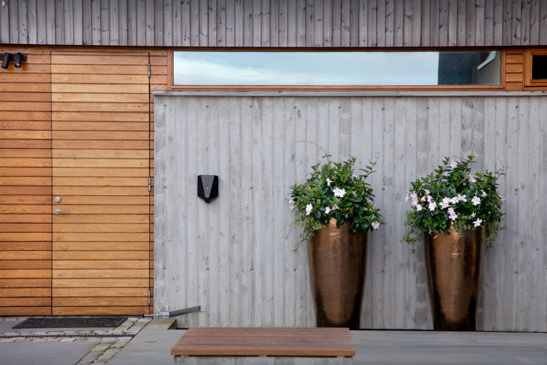 Een strak weggewerkte zwarte Easee laadpaal op een moderne betonwand, een voorbeeld van de esthetische 'Stoker Standaard'.