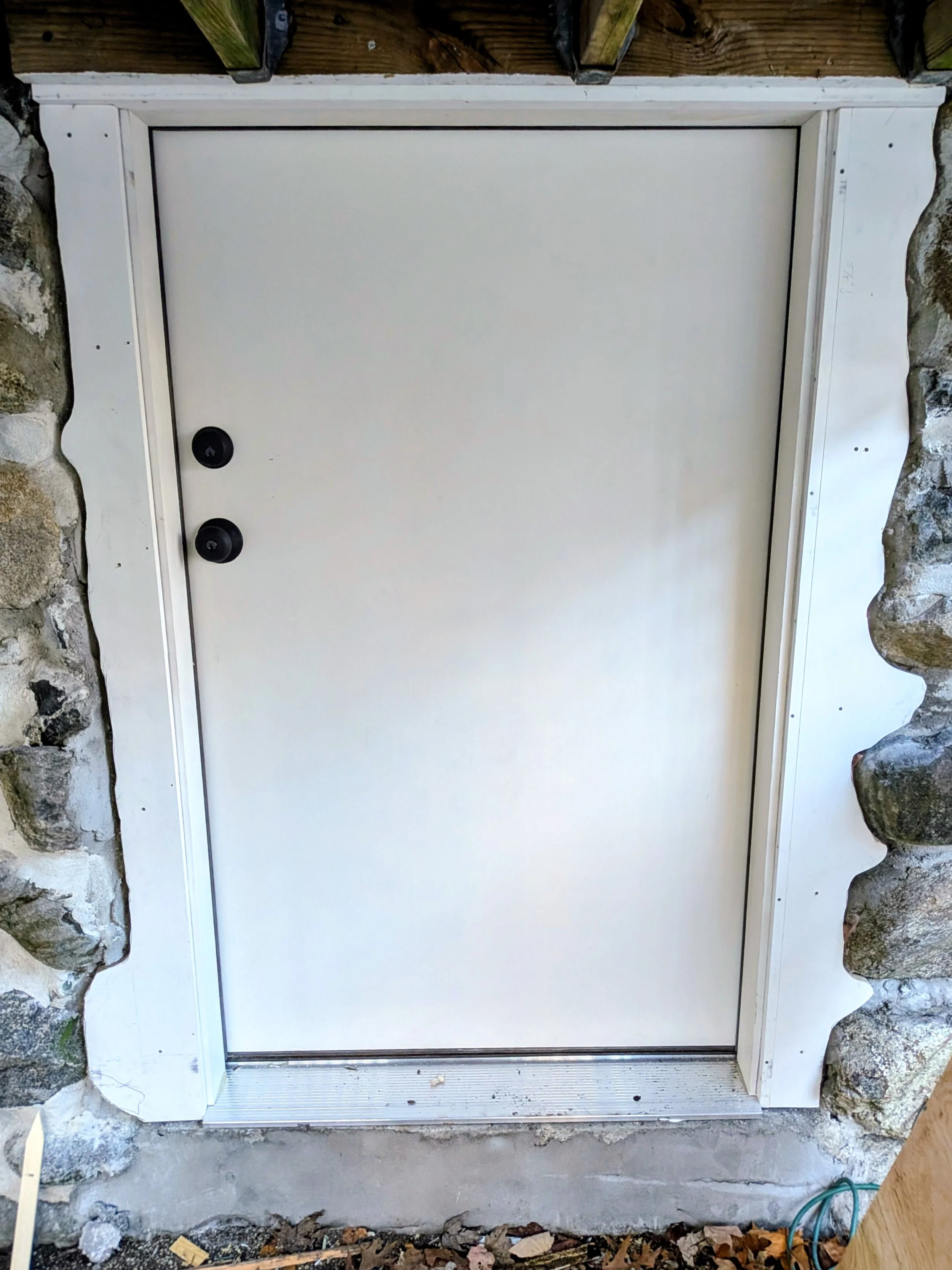 Scribed exterior basement door trim to stone wall