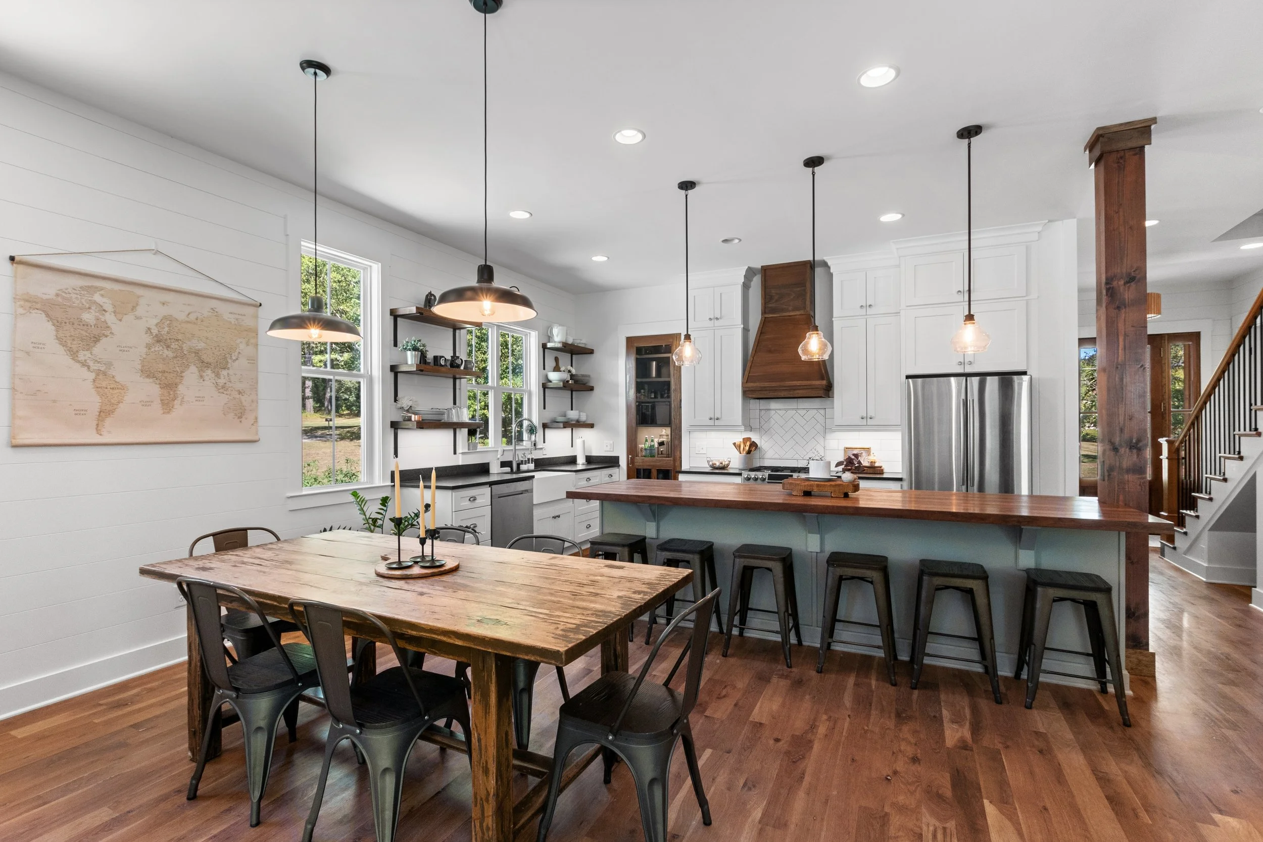 Modern kitchen with white cabinets, wooden accents, and a dining table with six black chairs.