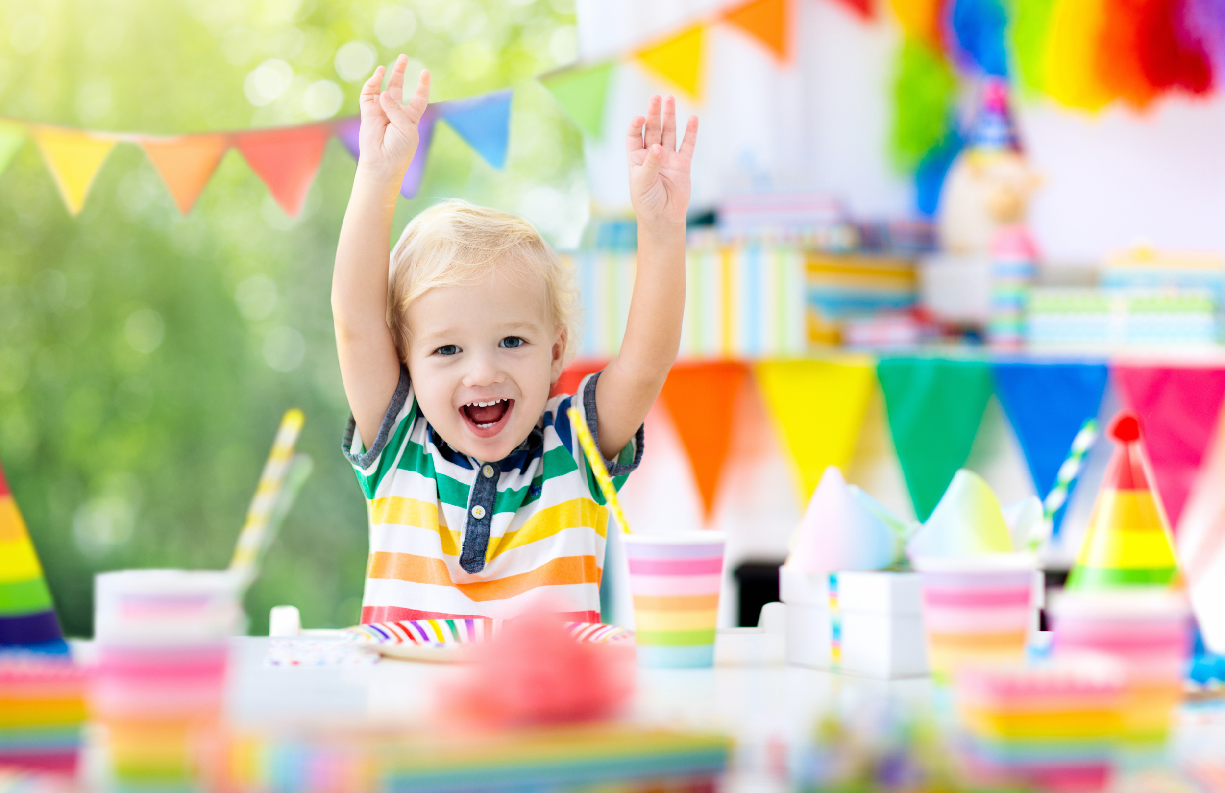 Child celebrating birthday party with colorful decorations, party hats, and striped cups. Bright sensory play gym at Kensington Valley Outlets.