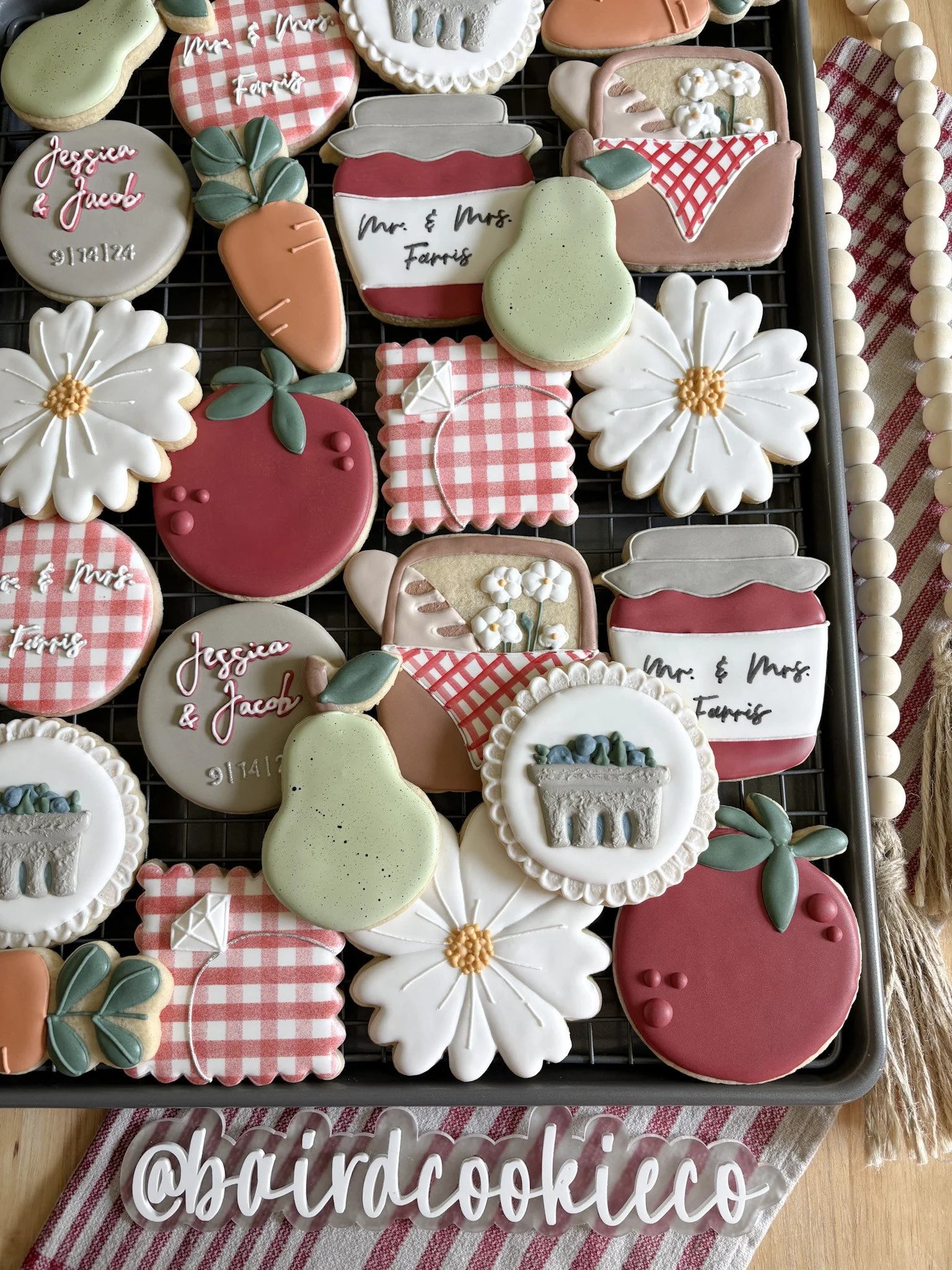 Colorful cookies with floral, fruit, and gift themes, decorated with icing, arranged on a cooling rack.