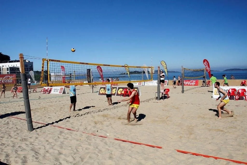 Personas jugando voleibol en la playa con el mar y el cielo azul de fondo.