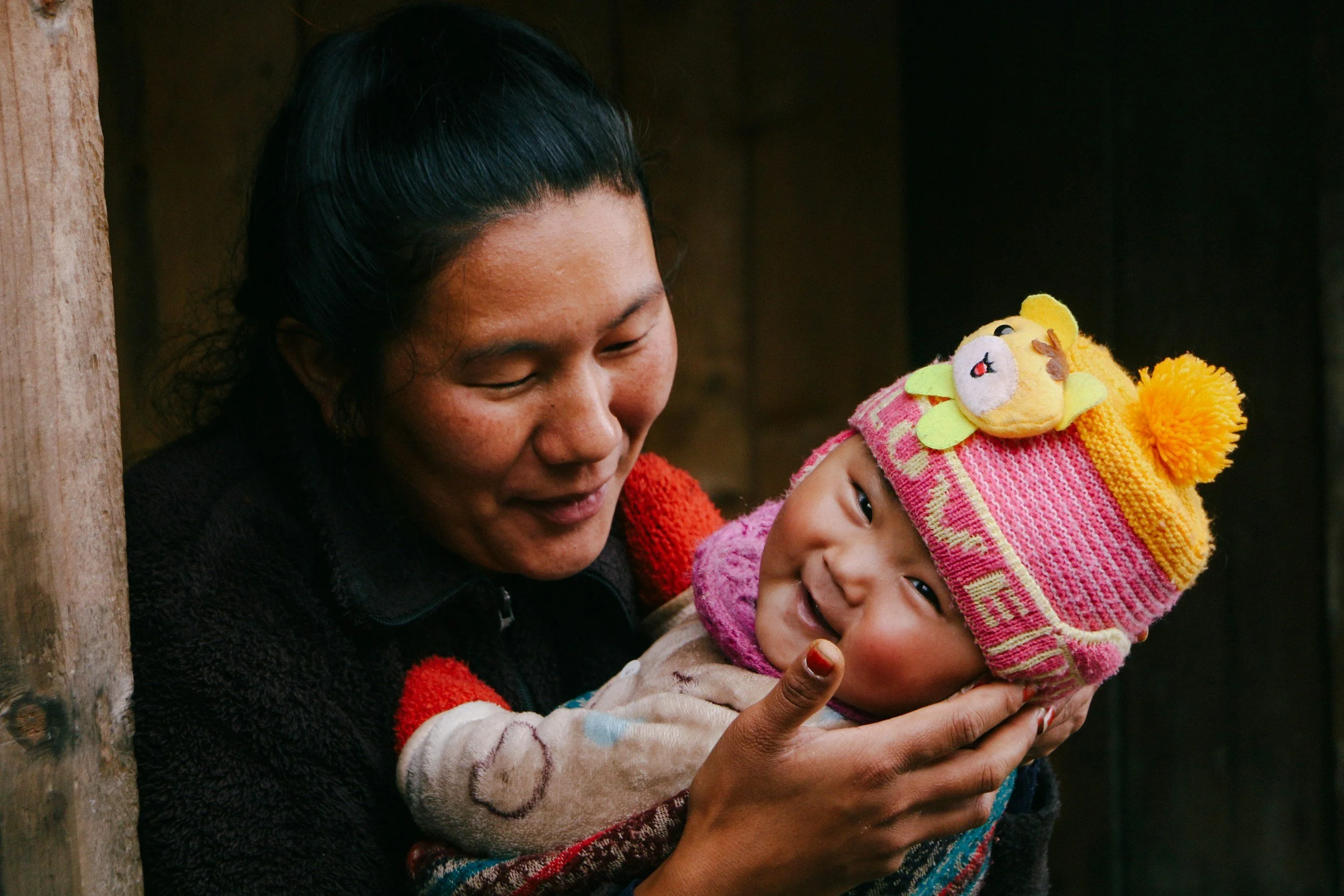 A woman embracing a child, with the woman looking down at the young child. Finch & Rose Counseling provides perinatal, postpartum, and child loss therapy for moms and folks who have given birth in Iowa.