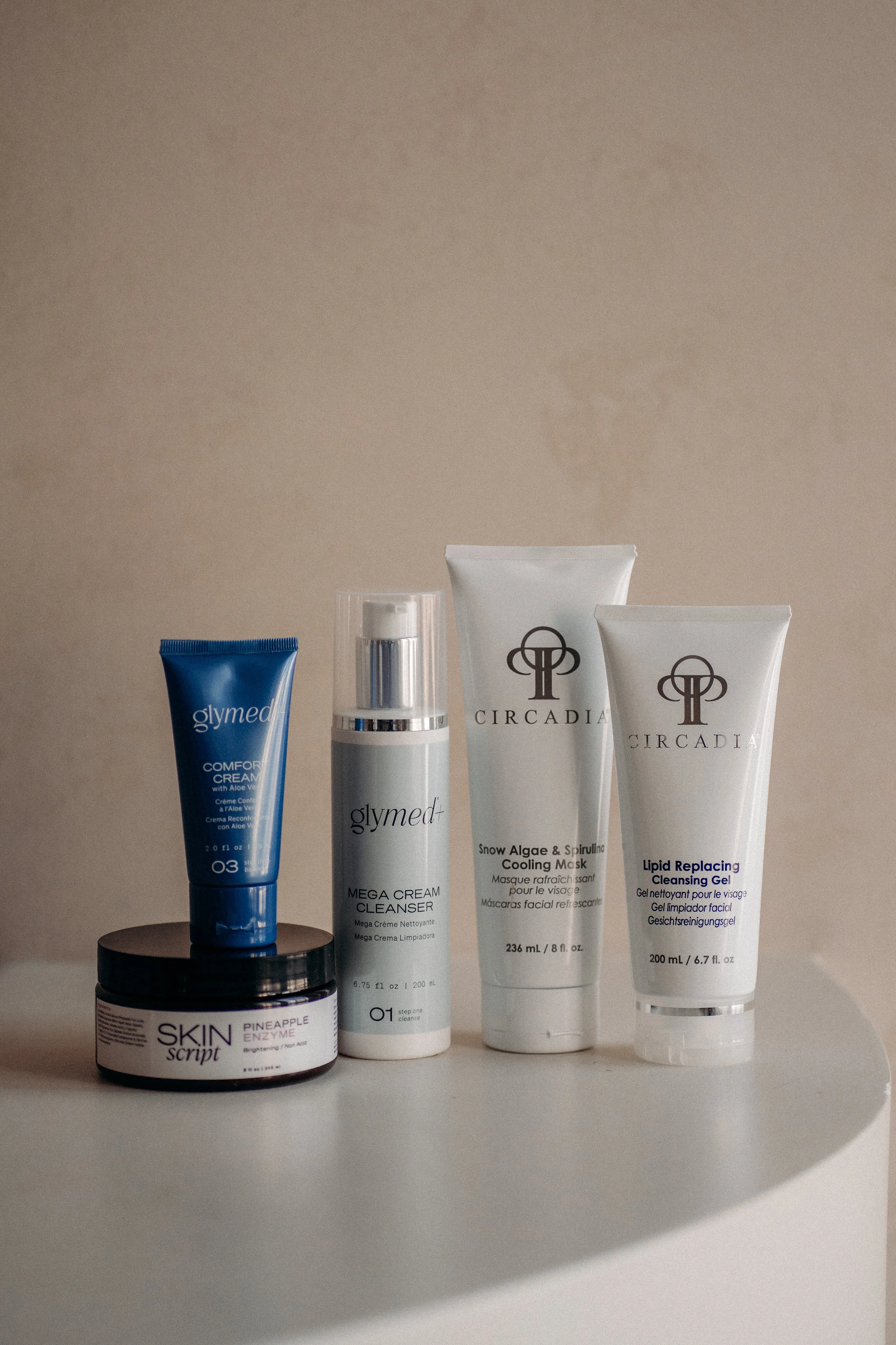 Skincare products including creams and masks on a white surface with a beige background. Products include Circadia, SkinScript and Glymed.