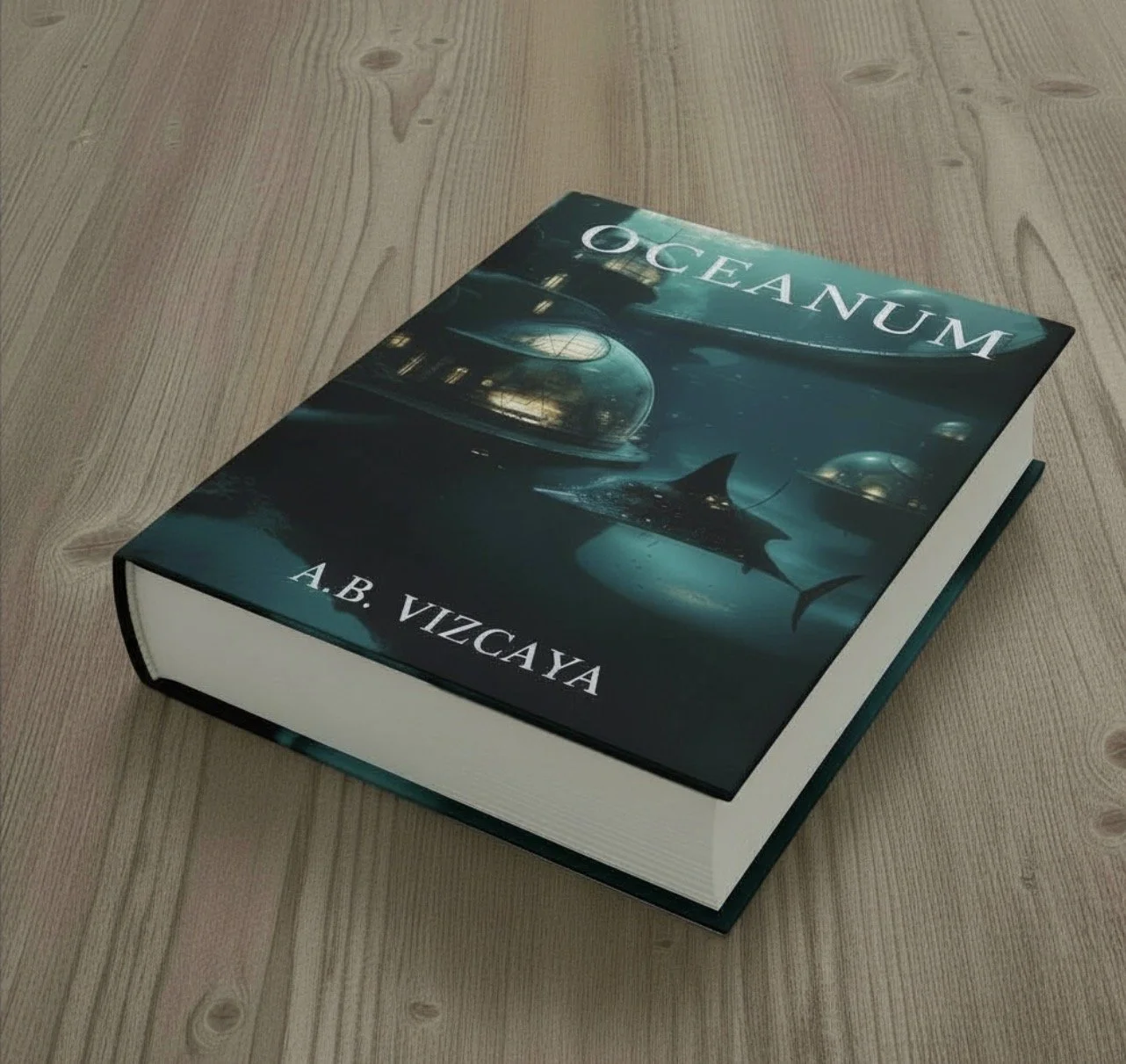 A hardcover book titled 'OCEANUM' by A.B. VIZCAYA, featuring an underwater scene with a shark and futuristic domed structures illuminated in blue on the cover, resting on a wooden surface.