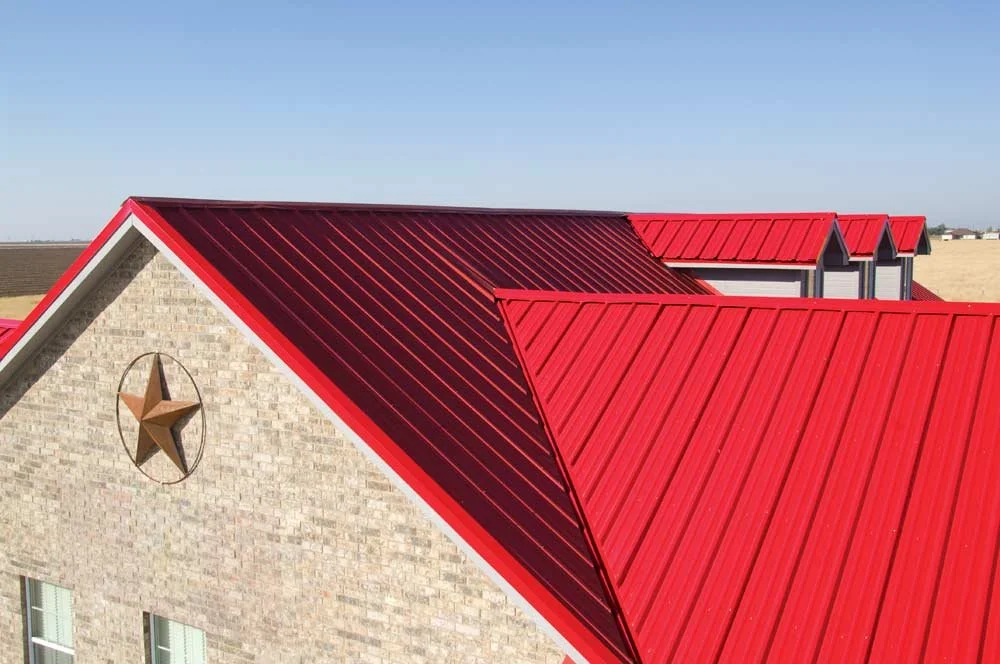 Close-up of a house with red metal roof, a brick wall, and a decorative star on the wall.