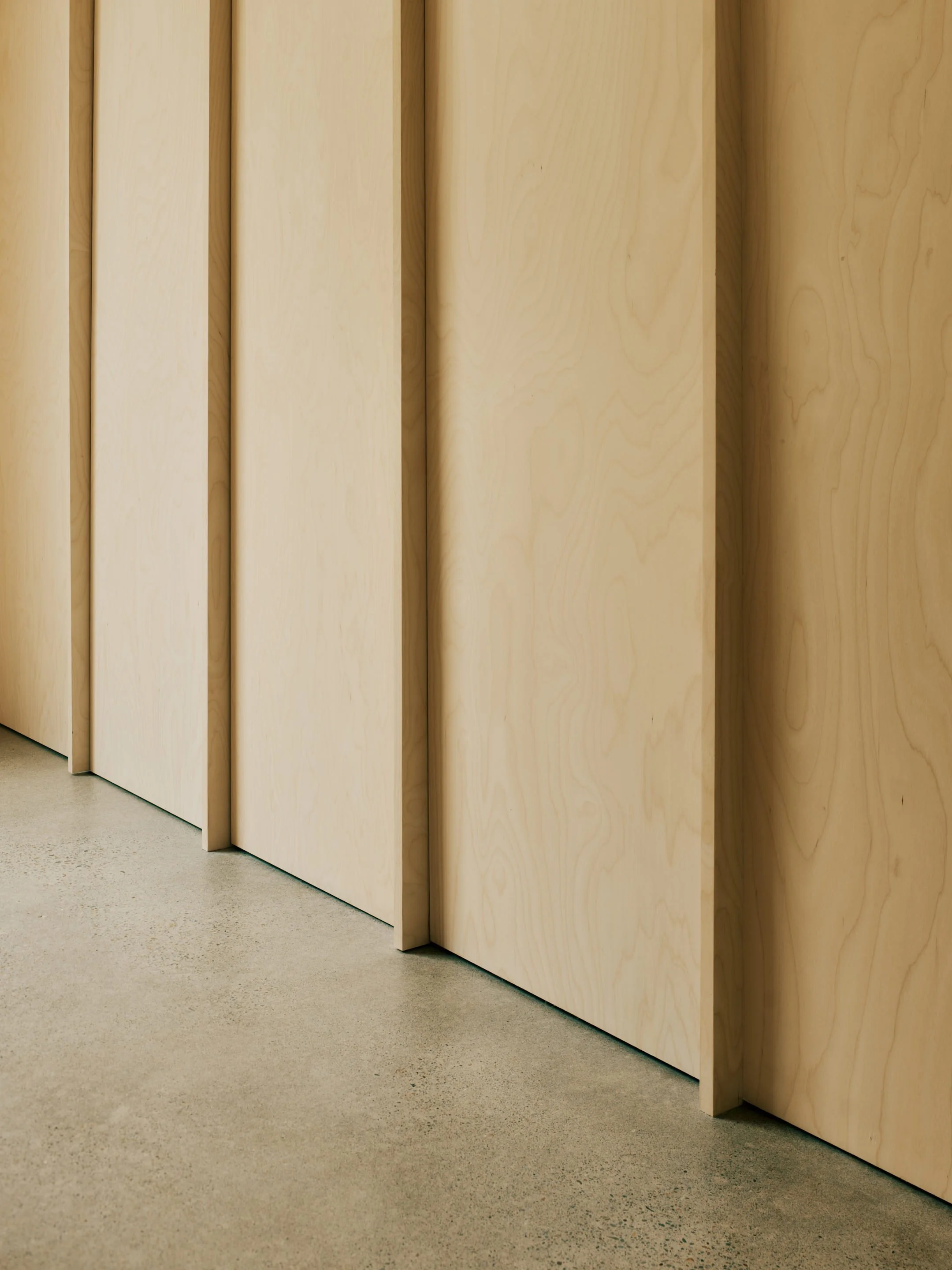 Wooden panel walls in an pool house with a beige, textured floor.