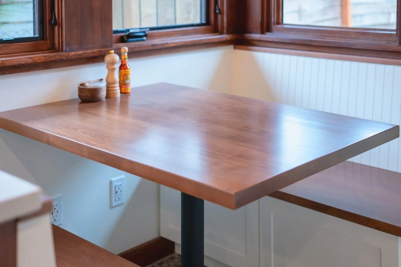 Rich wood toned cabinets and window trim and white countertops and walls make a seamless transition from the kitchen to the newly remodeled seating area.
