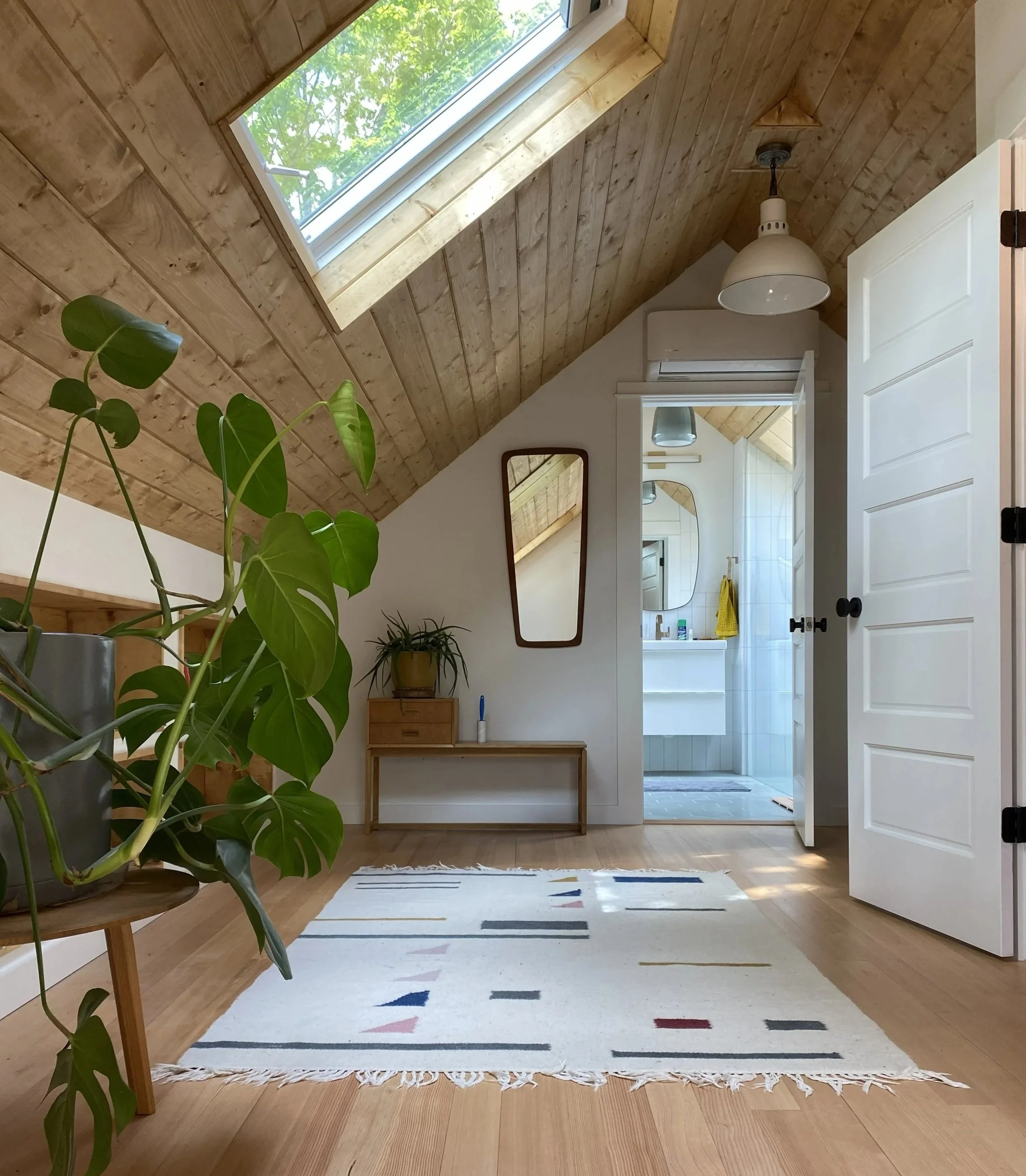 The remodeled attic has plenty of room for plants, shelves, a chair. The doorway to the bright bathroom is on the opposite end.