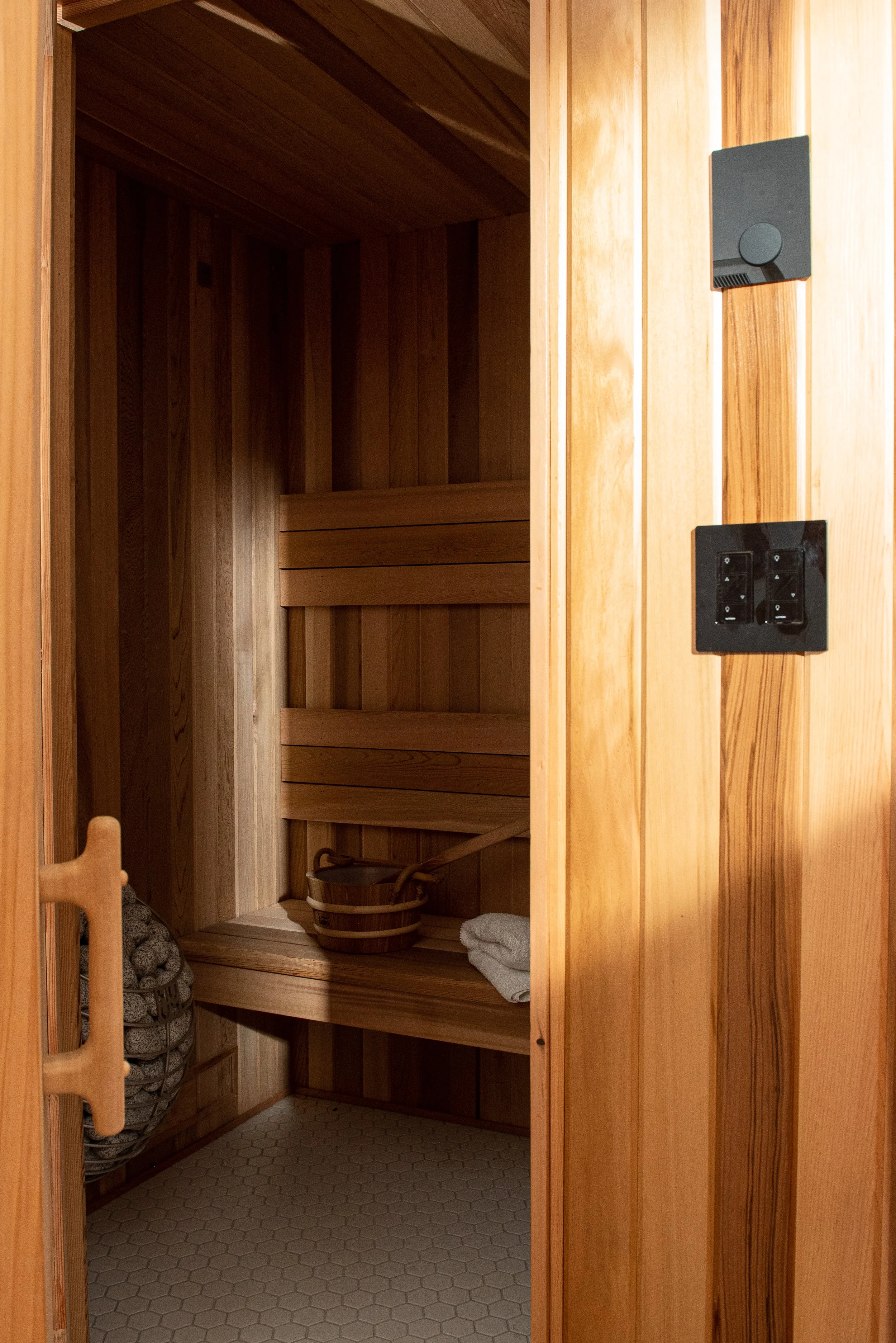 A view from the doorway into this basement sauna renovation, with perpendicular textures of the cedar wood paneling on the inner walls.