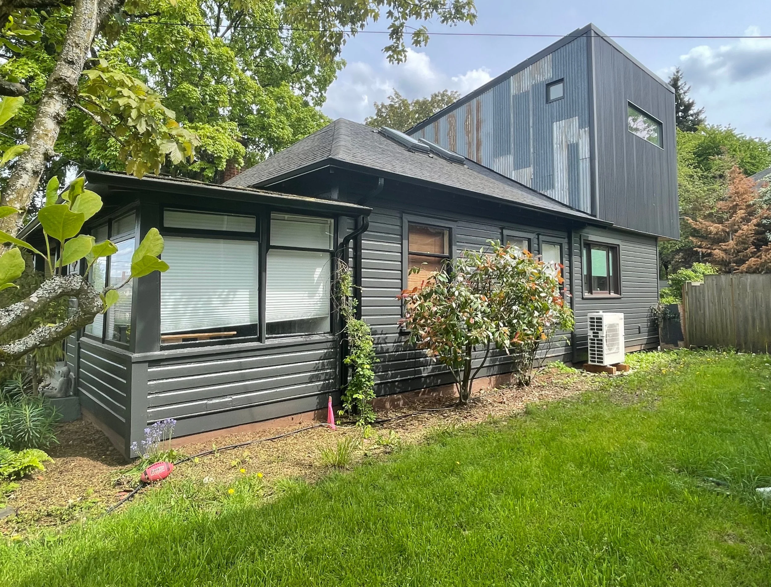 The siding of this remodeled house is dark grey with interesting and unique textures and angles.