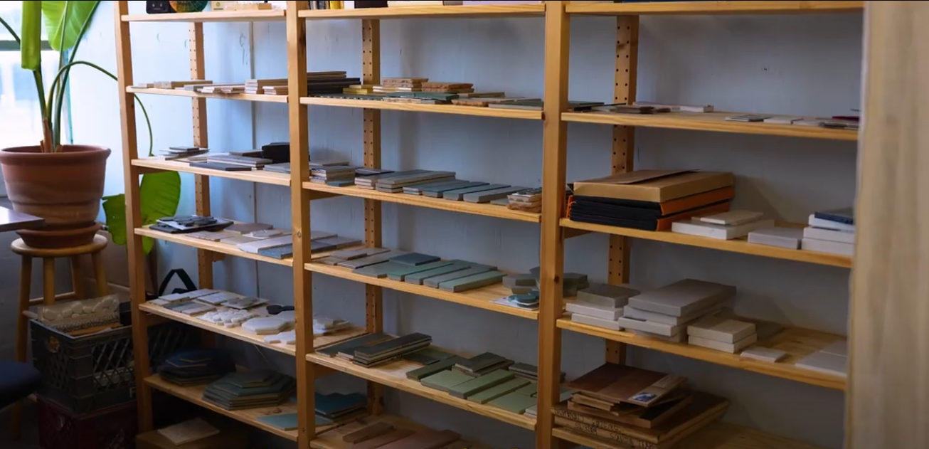 Wooden shelves filled with sample tiles and materials in various rich and earthy colors and sizes.