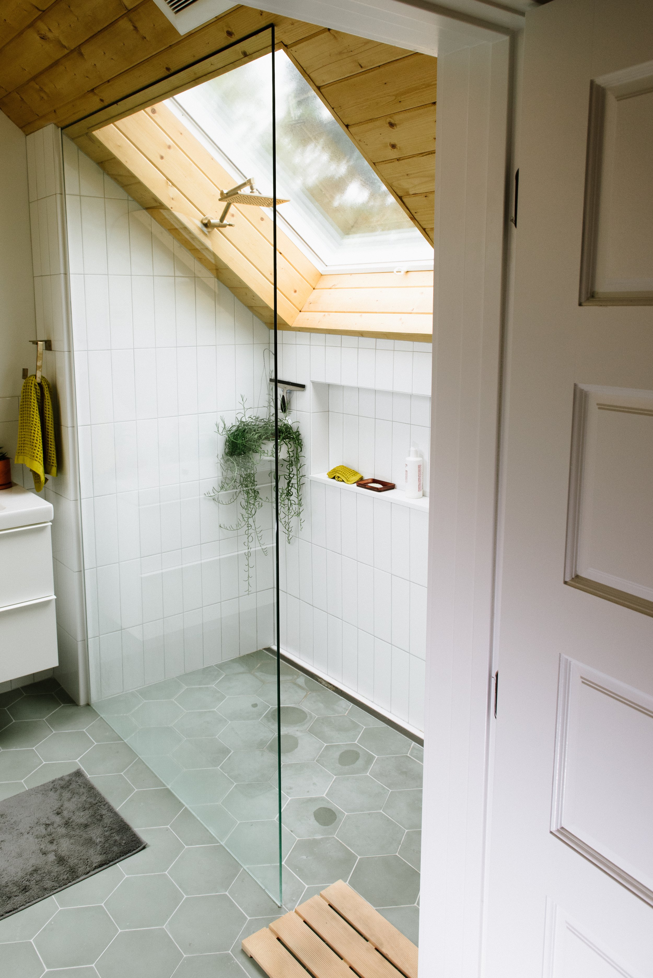 This small bathroom has plenty of light from the skylight over the shower and grey hexagonal floor tiles.