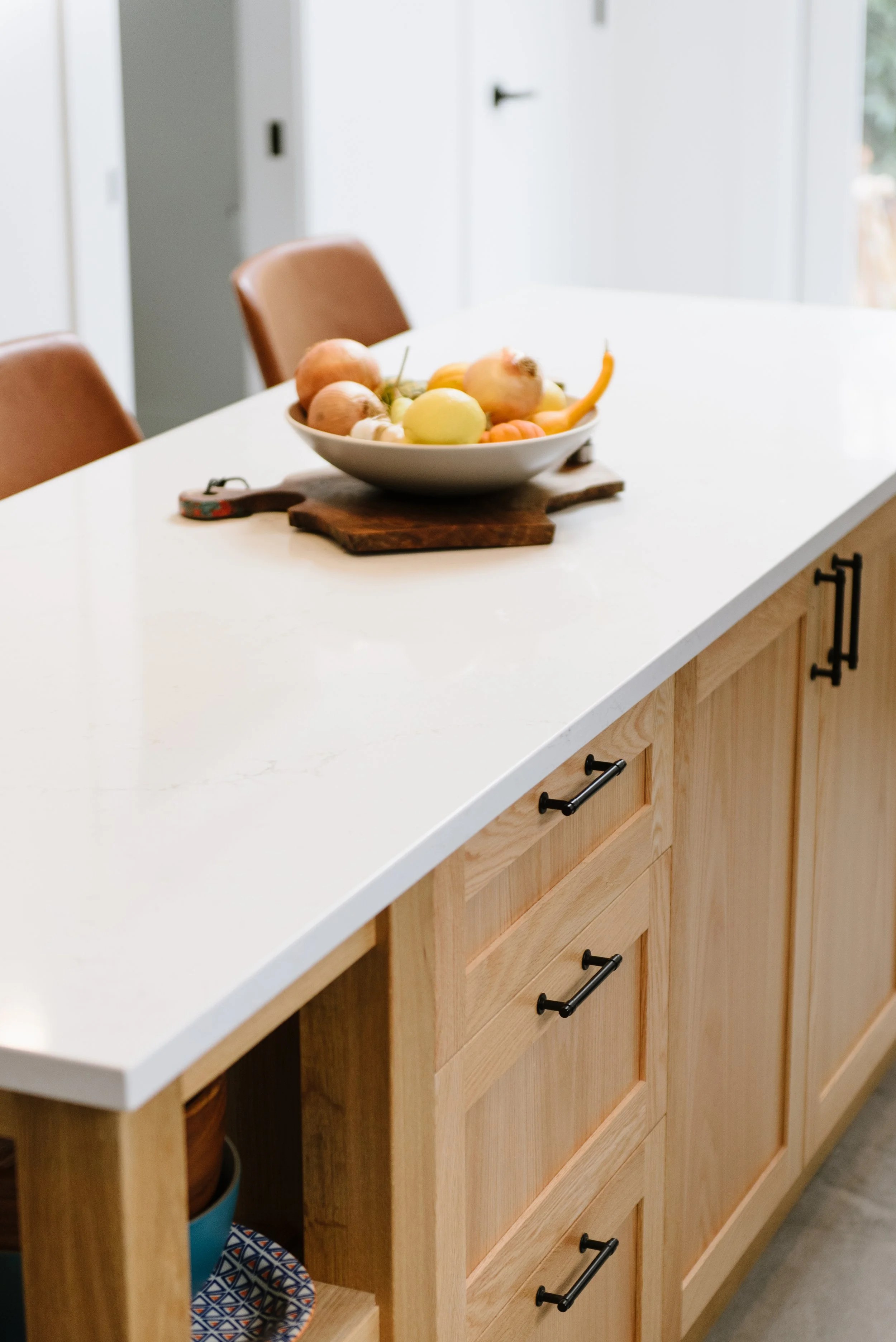 This renovated kitchen seating area has soft leather stools on one side and cabinets on the other side.