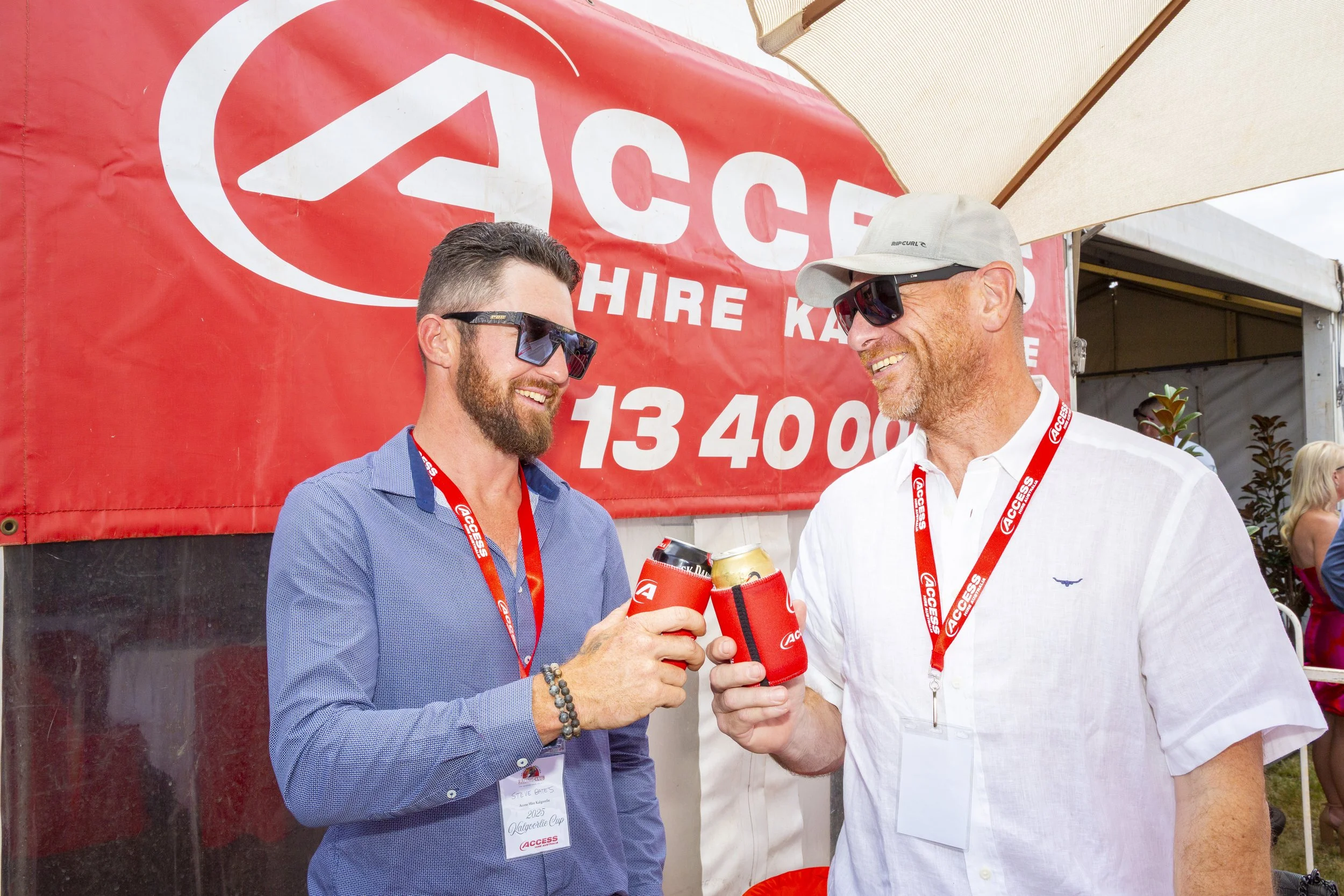 Outdoor arena with a field, a large screen, white chairs, and a yellow and blue structure in the distance, under a blue sky with scattered clouds.