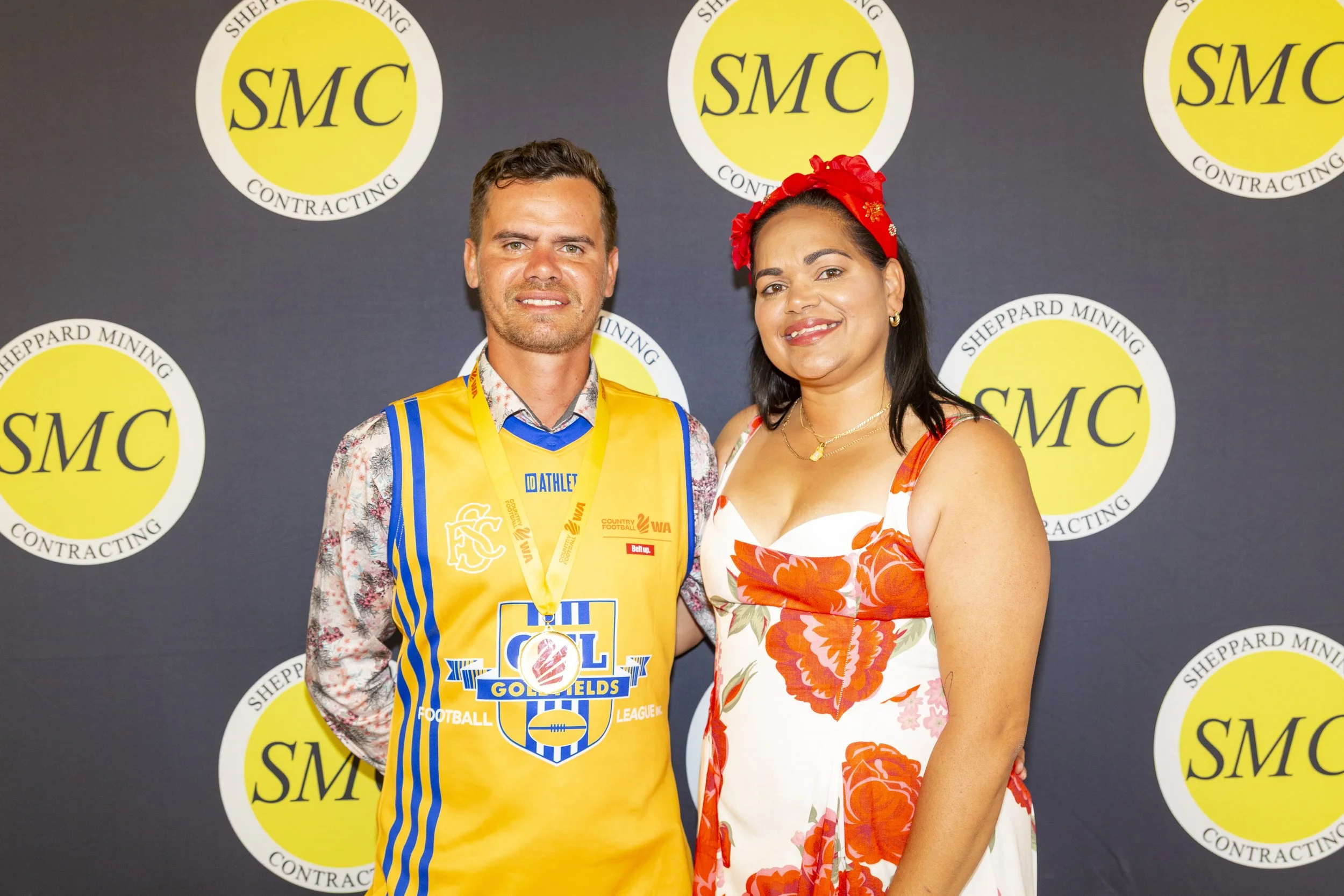 Audience sitting at round tables in a large decorated event tent, watching a performance or presentation on a stage.