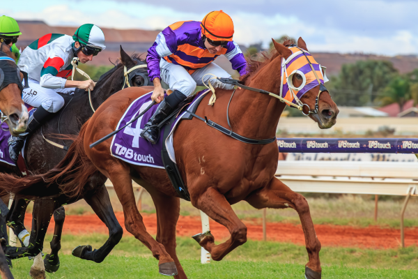 Racehorses competing on a dirt track, with jockeys wearing colorful uniforms and helmets, during a horse race.